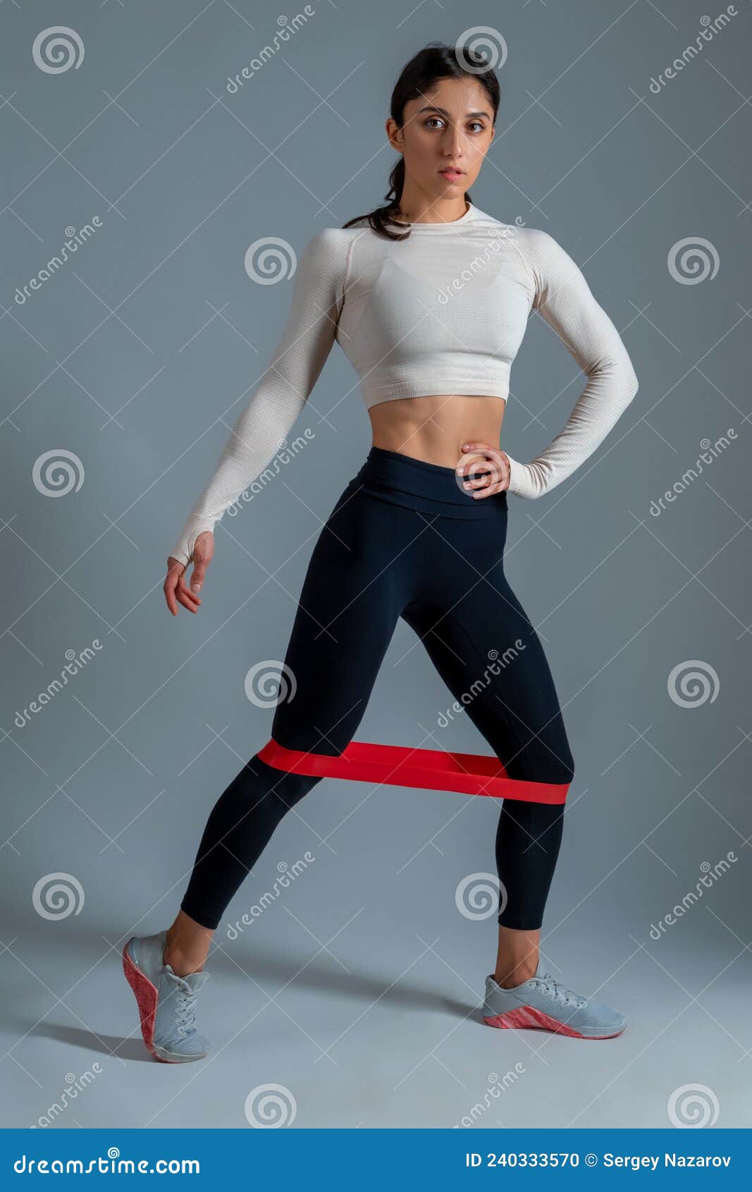 Premium Photo  Woman uses elastic band for workout dressed in activewear  poses on fitnes mat on shoulders wears activewear smartwatch sneakers poses  outside in urban surroundings