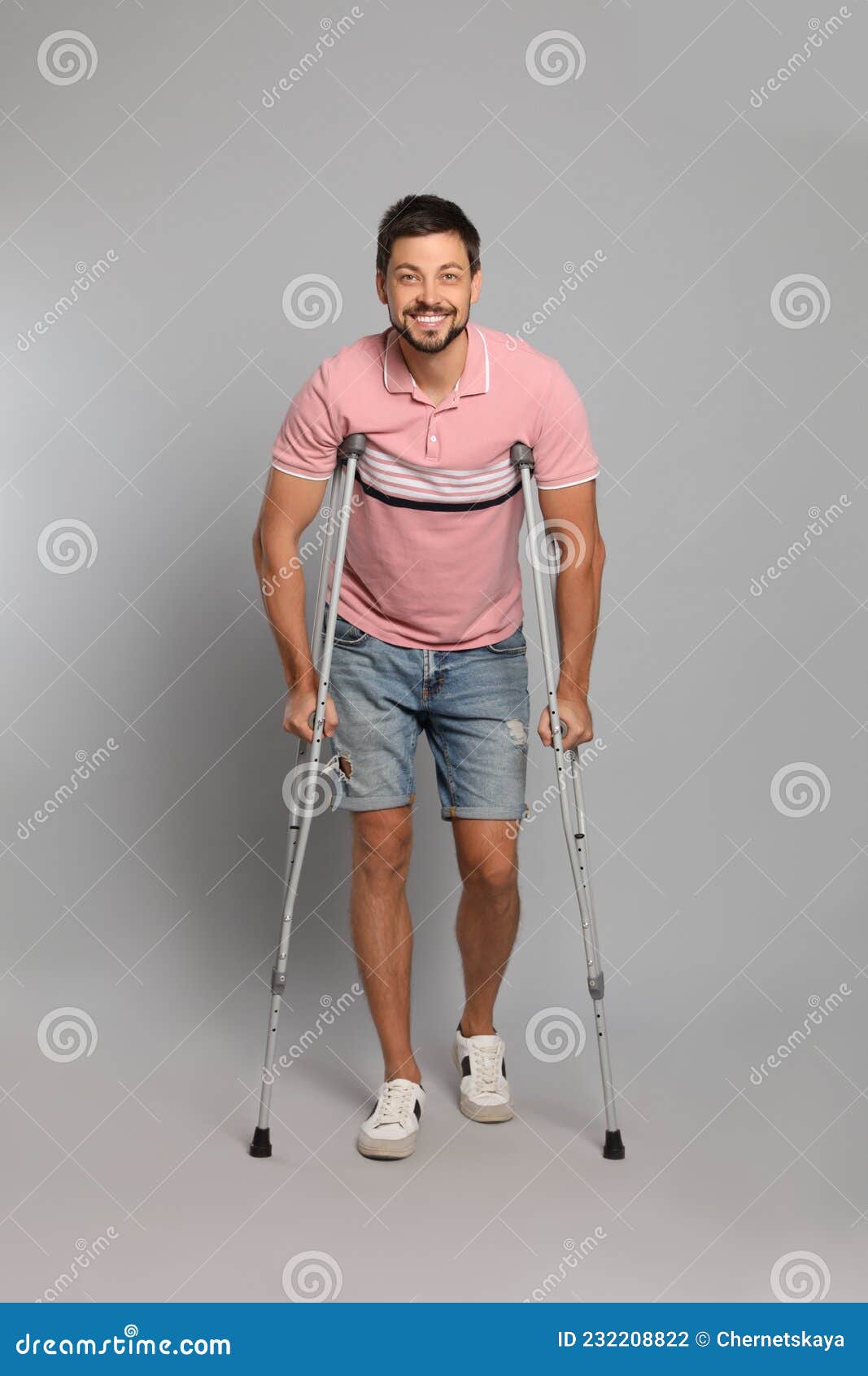 Full Length Portrait of Man with Crutches on Grey Background Stock