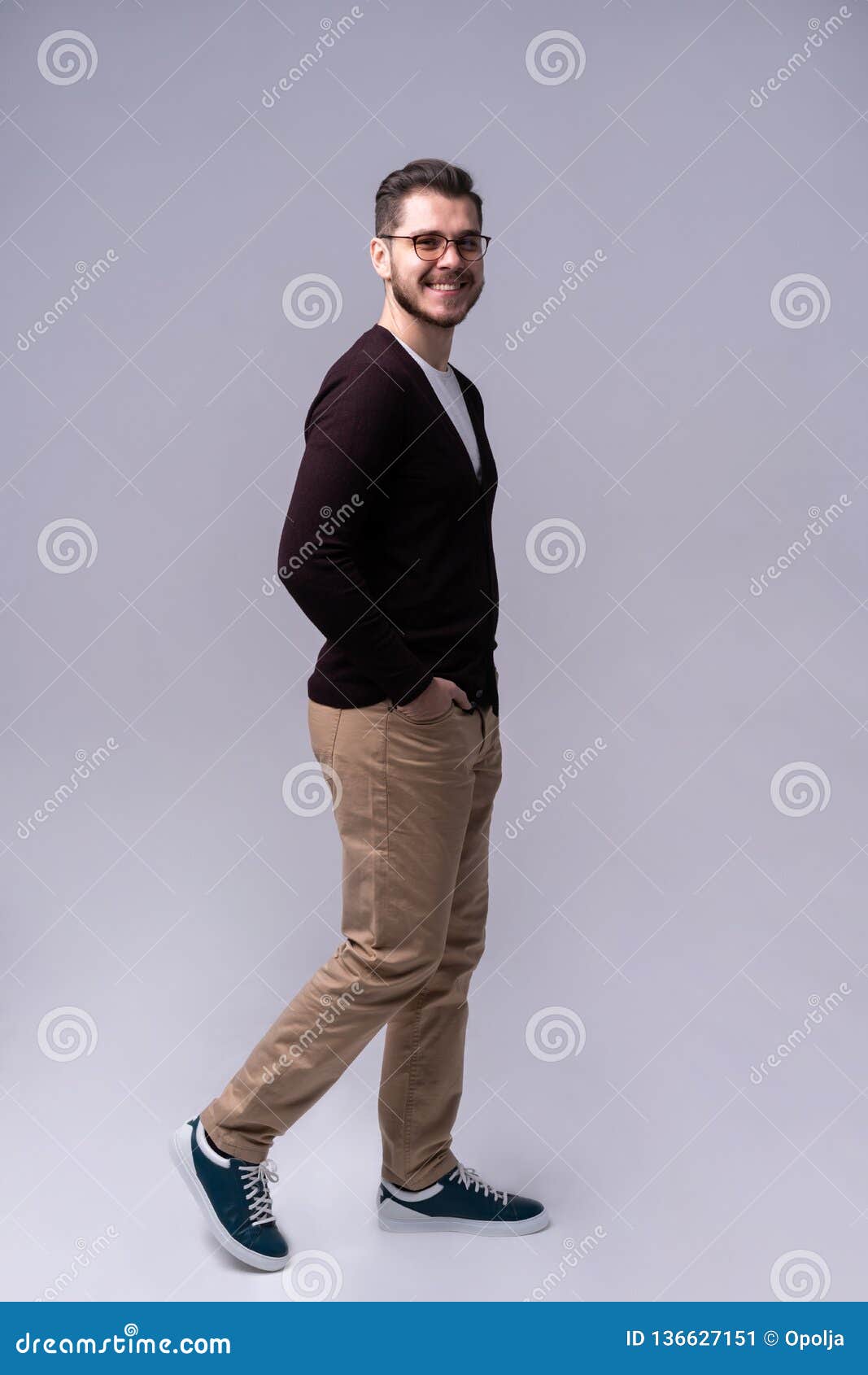 Full Length Portrait of a Smiling Young Man Walking Isolated Over Gray ...