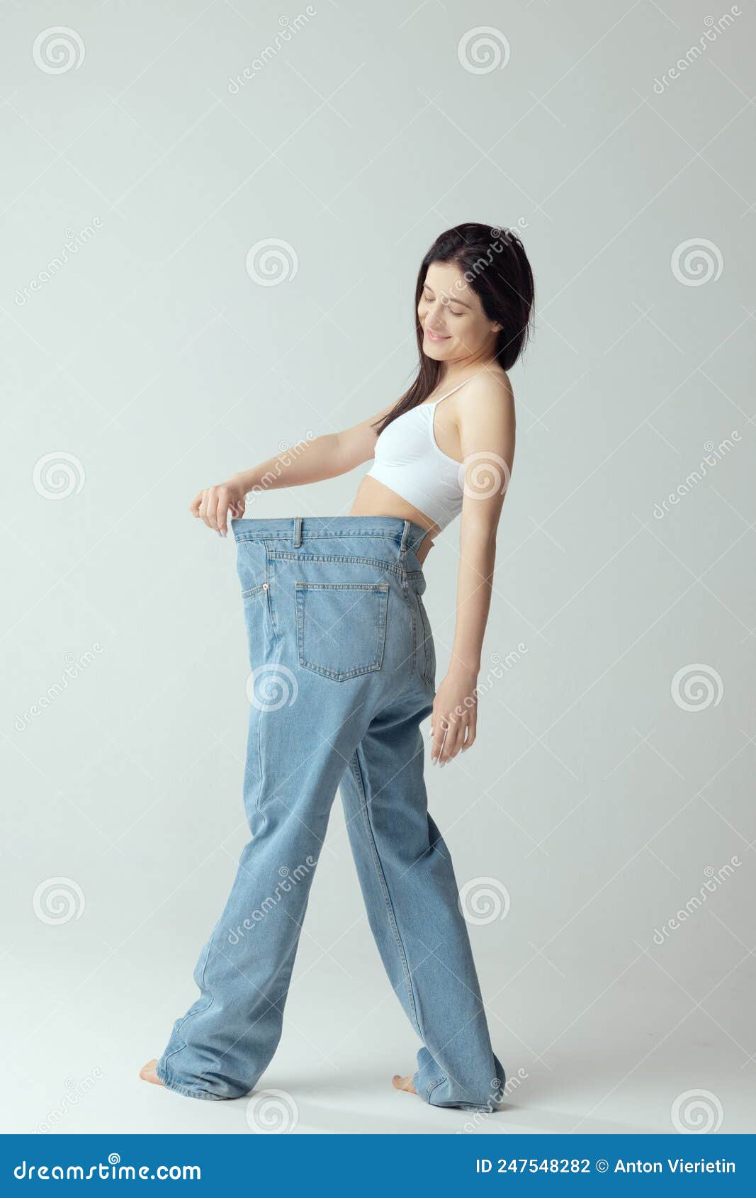 Full-length Portrait of Young Slim Woman Wearing Giant Jeans, Posing ...