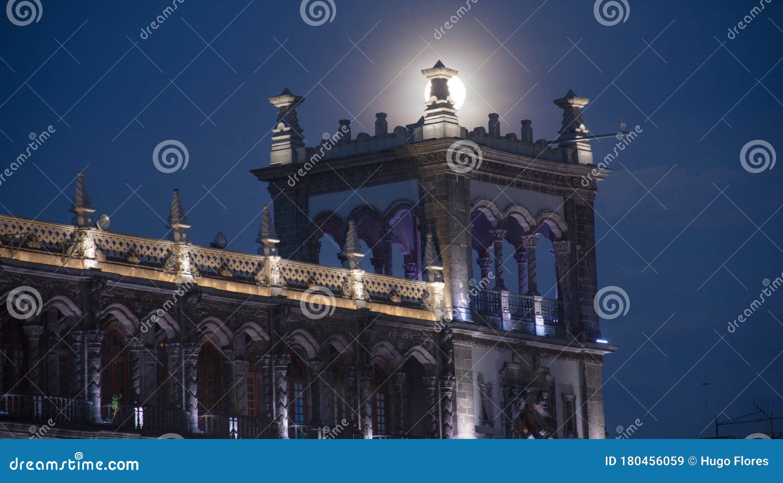 the full moon behind the ancient architecture in a city