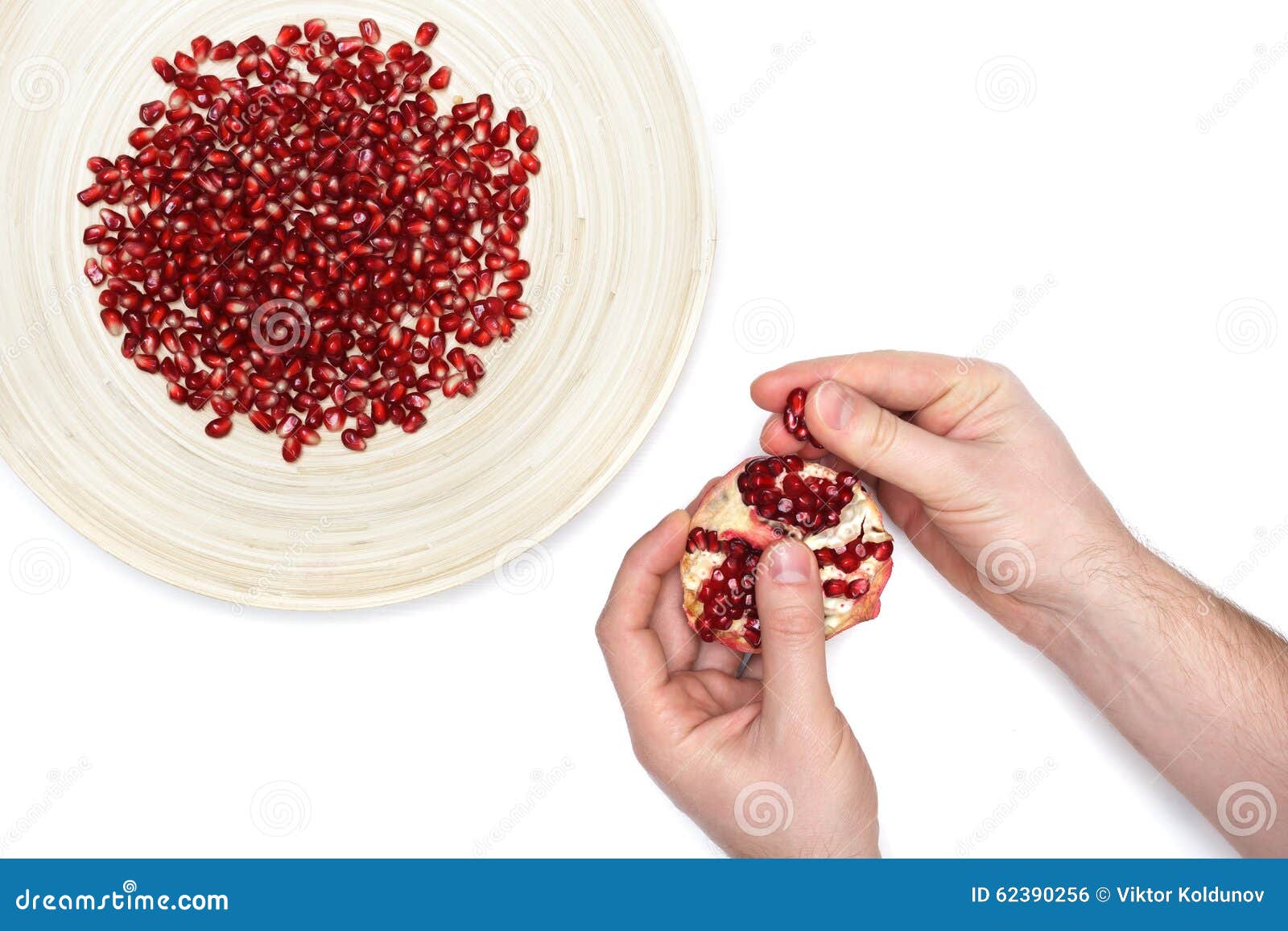 full plate of peeled pomegranate seeds and a man de-seeding gran