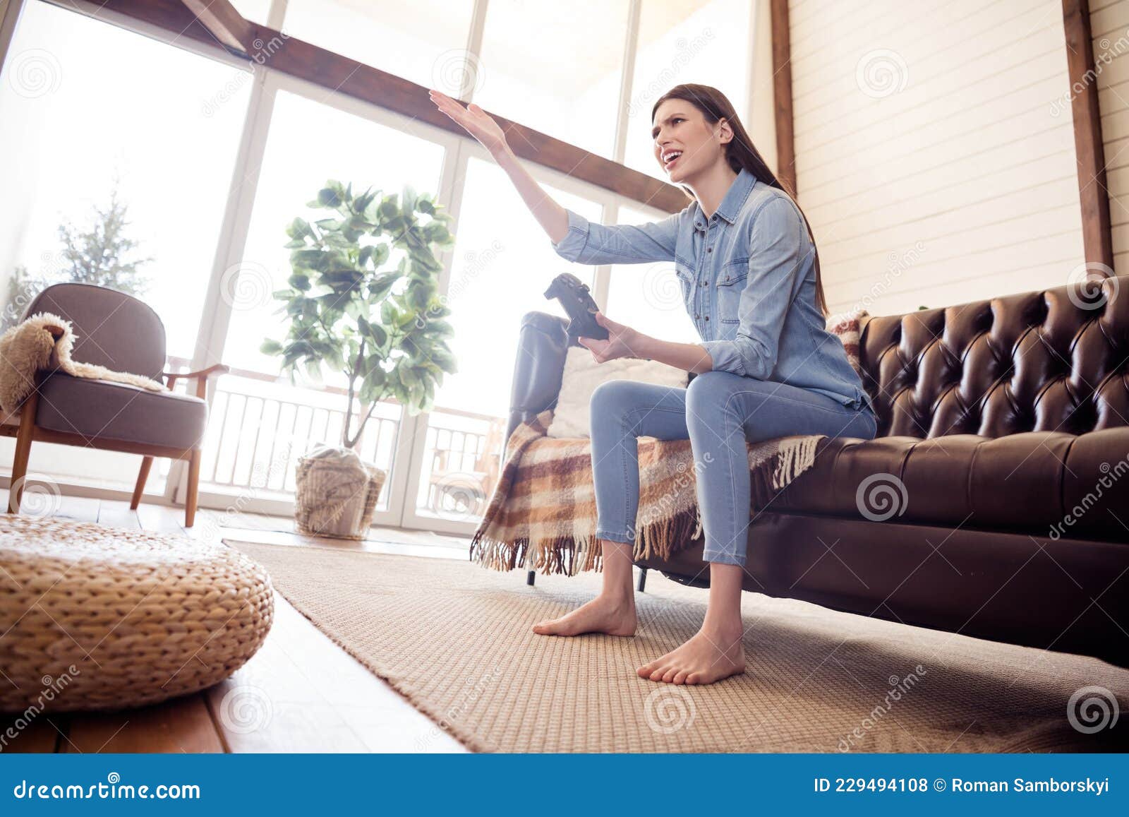 full size photo of unhappy upset young woman hold hand joystick play game sit sofa indoors inside house