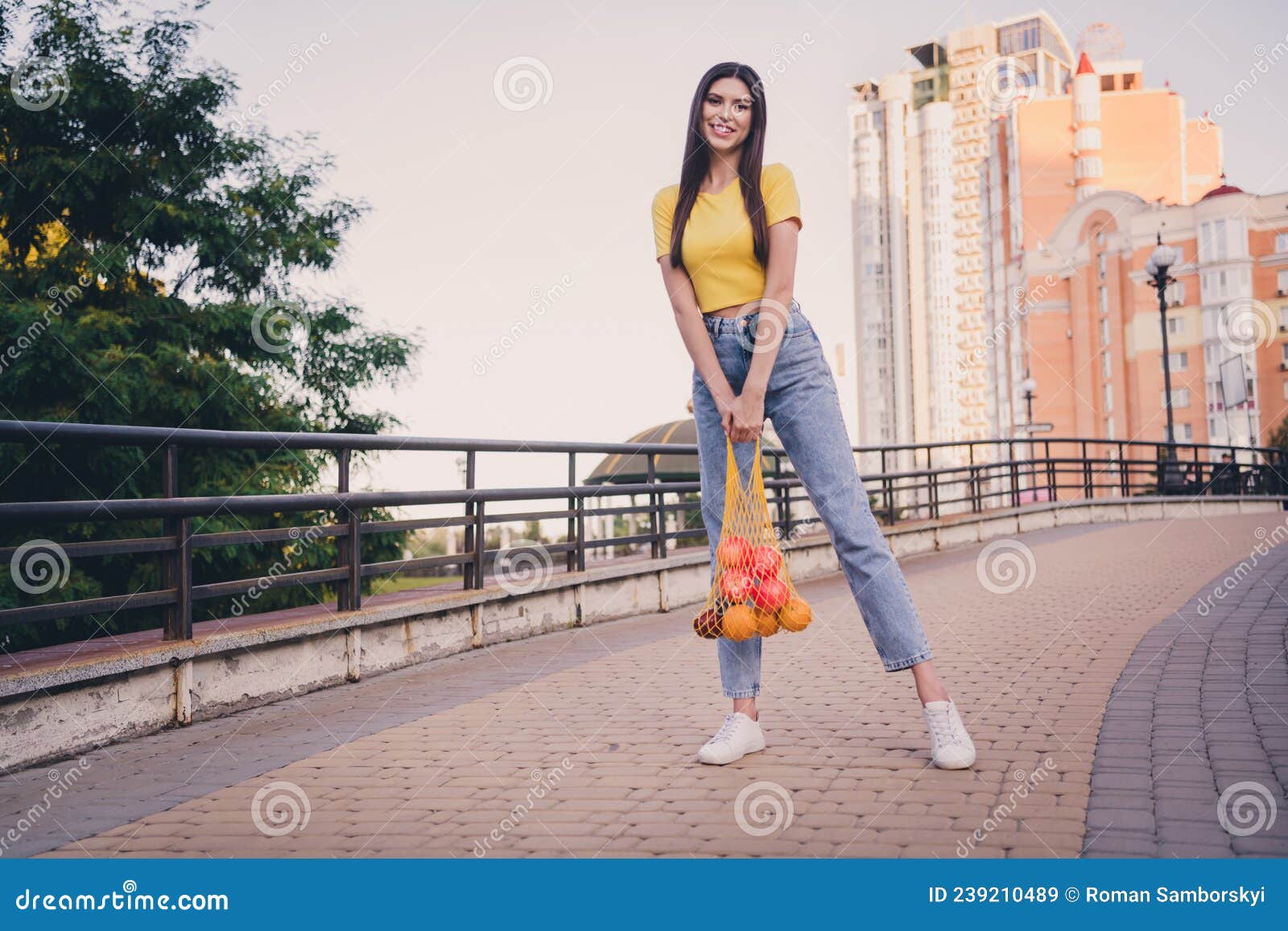 full size portrait of adorable cheerful young lady hands hold fresh fruits net toothy smile look camera outside