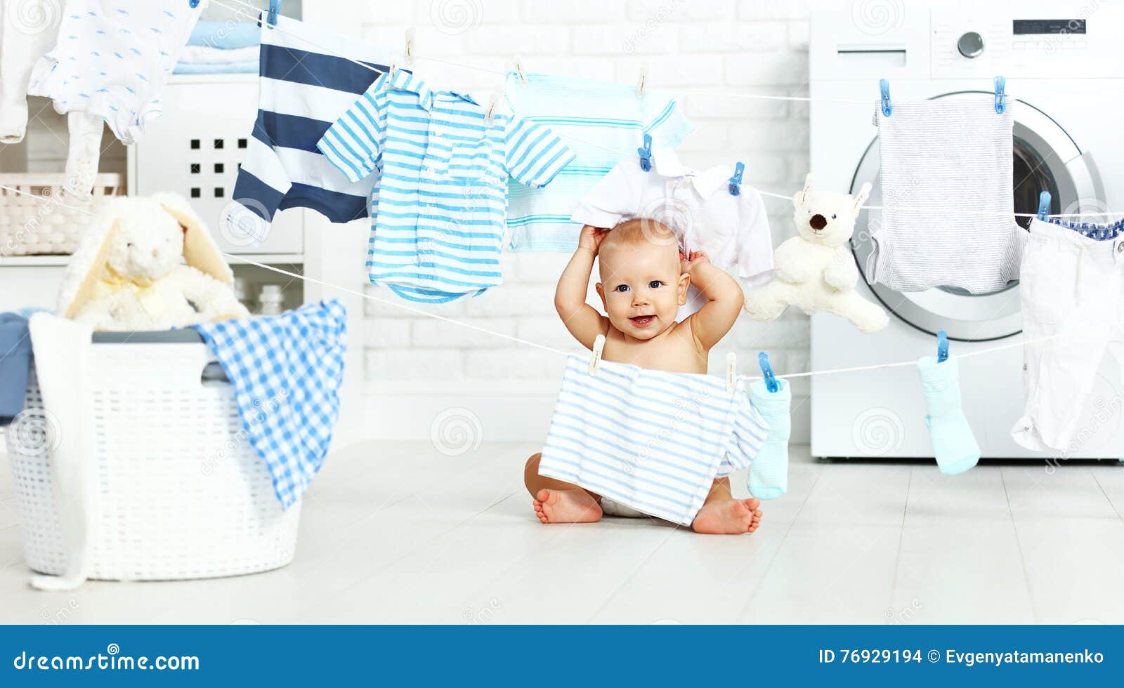 fun happy baby boy to wash clothes and laughs in laundry
