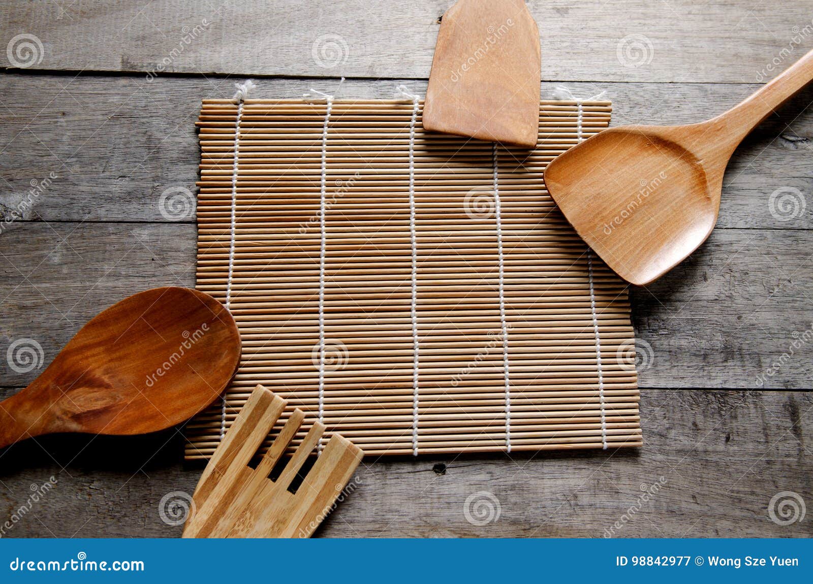 Fundo para cozinhar o conceito. Esteira do utensílio de cozimento e a de bambu na tabela de madeira