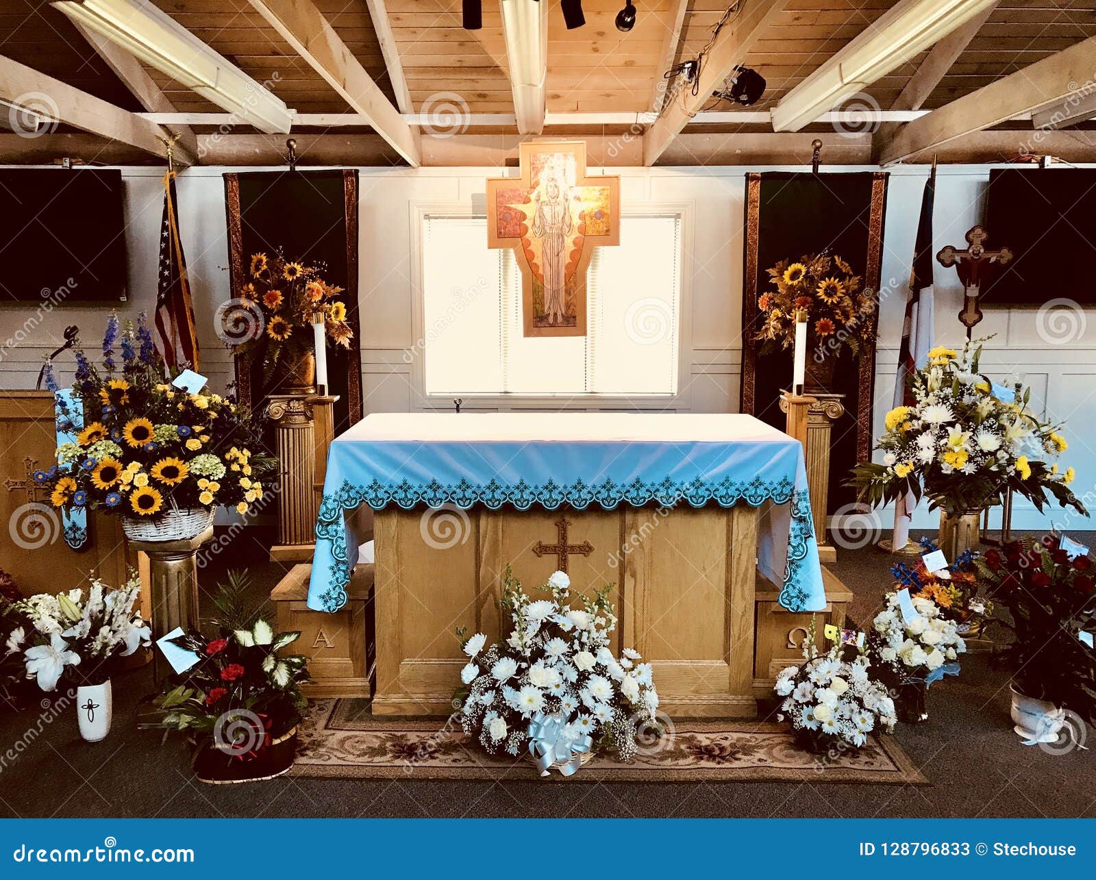 a funeral service is prepared in a church with a cross, flowers, and a flag
