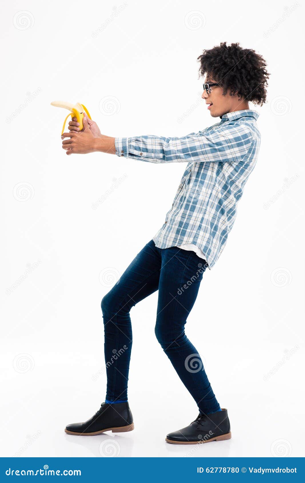 Side view portrait of a funny afro american man aiming from banana isolated on a white background