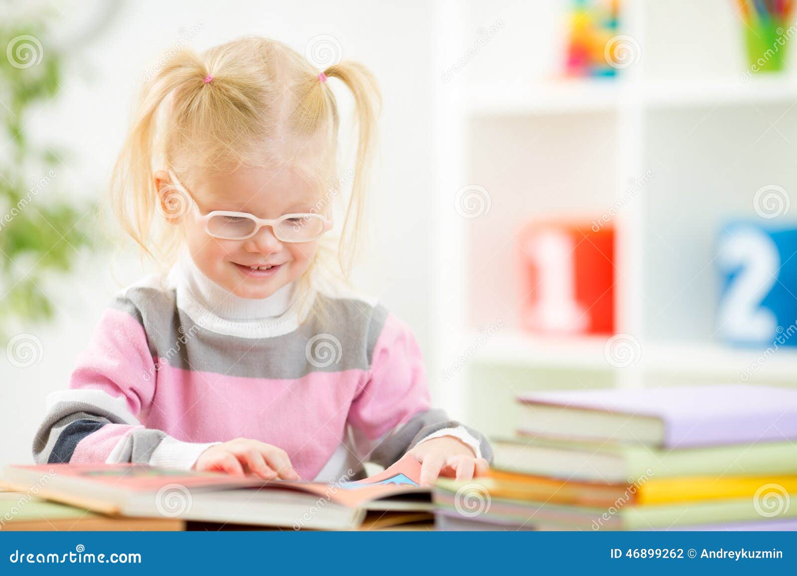 funny child in eyeglases reading book at home