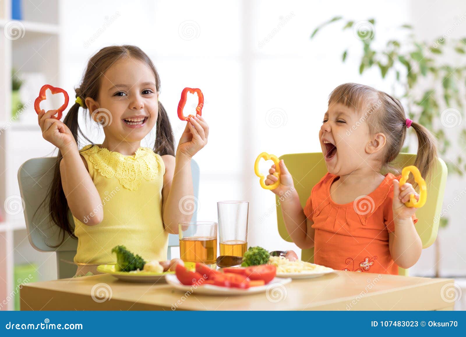 funny children girls eating healthy food. kids lunch at home or kindergarten.