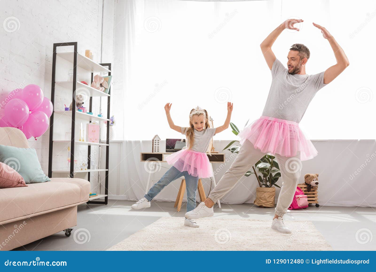 funny father and daughter in pink tutu skirts dancing