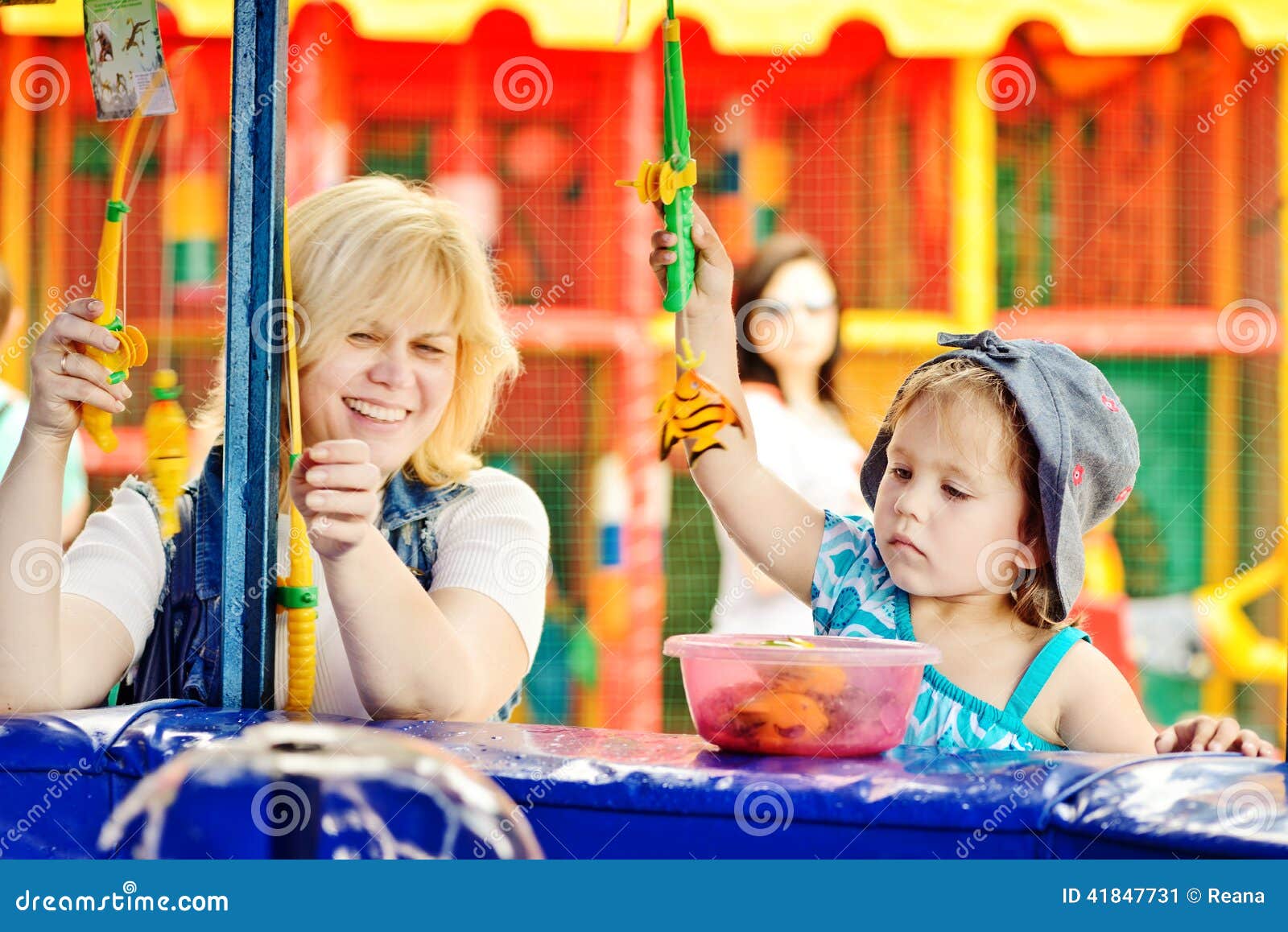 Funny fishing of mother and daughter in amusemen park.
