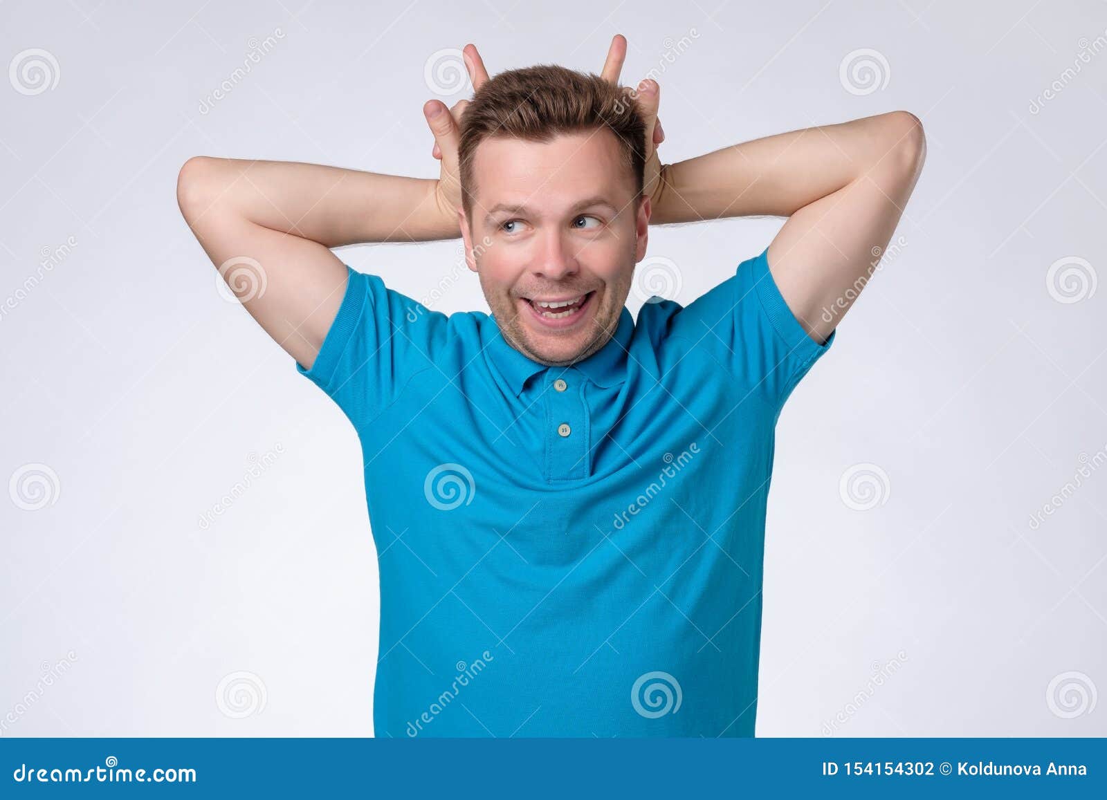 Surreptitious Gesture With The Head Man Standing with Horns Hand Gesture on Head and Looking at Camera