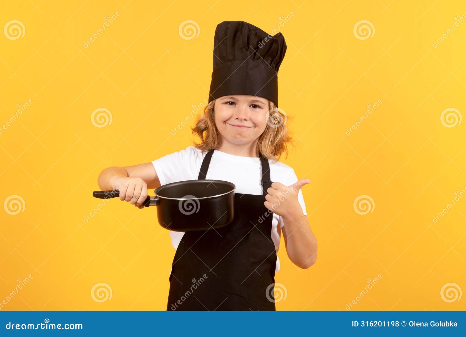 funny kid chef cook with kitchen pot stockpot. kid in cooker uniform and chef hat preparing food on studio color
