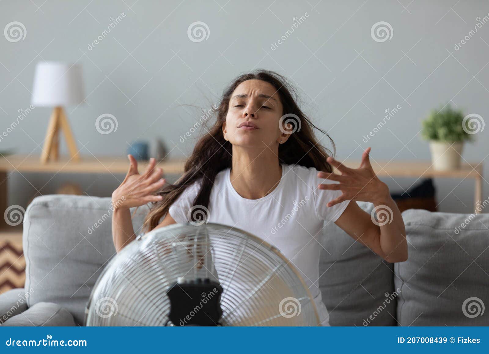 funny overheated woman enjoying fresh air, cooling by electric fan