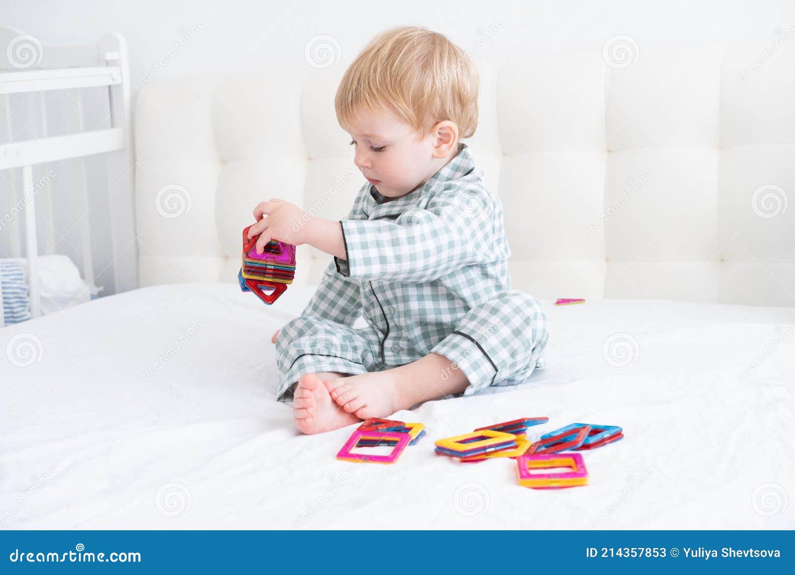 Funny Toddler Boy Playing in Constructor on White Bed in