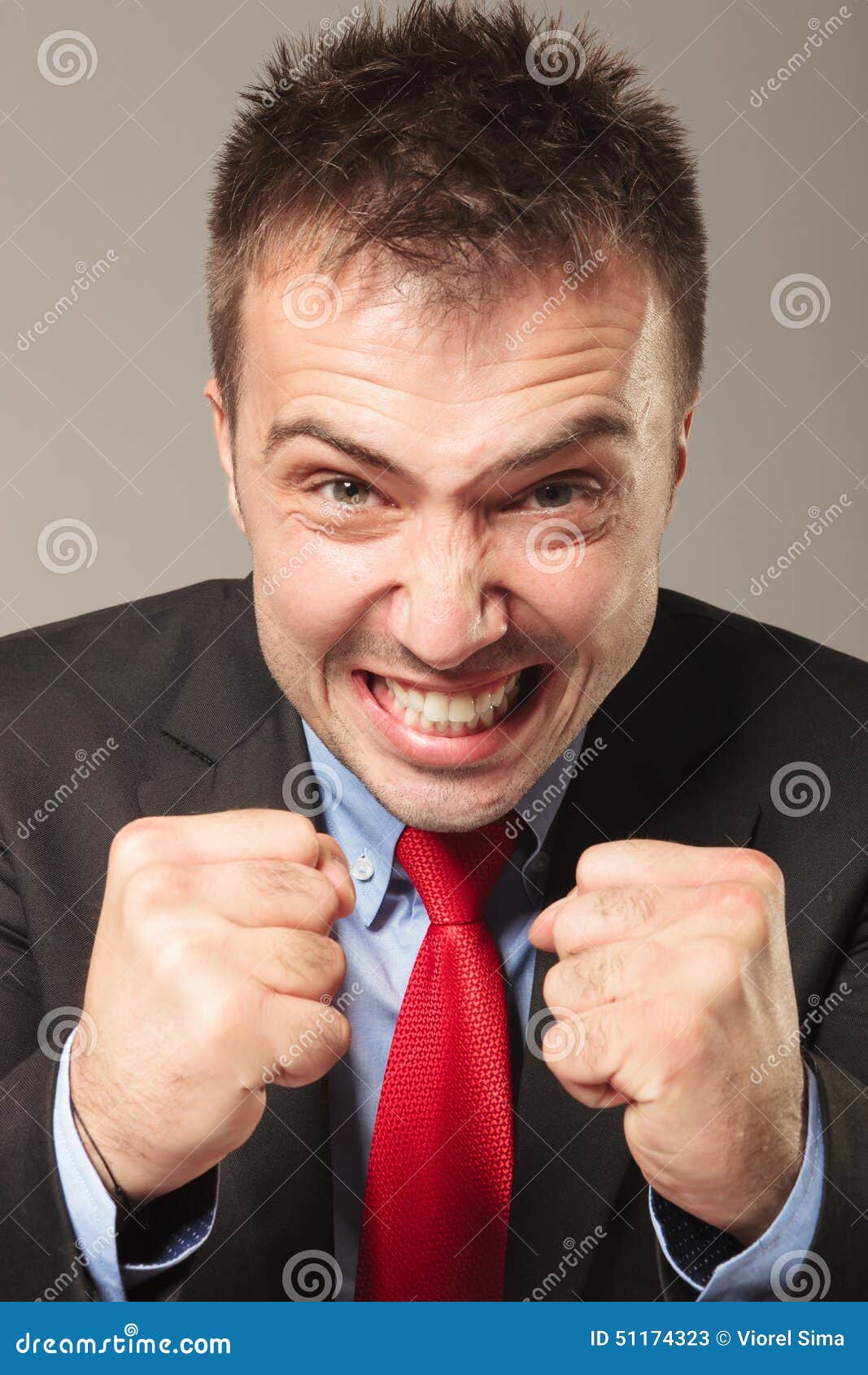 Furious business man making a angry face while showing you his fists