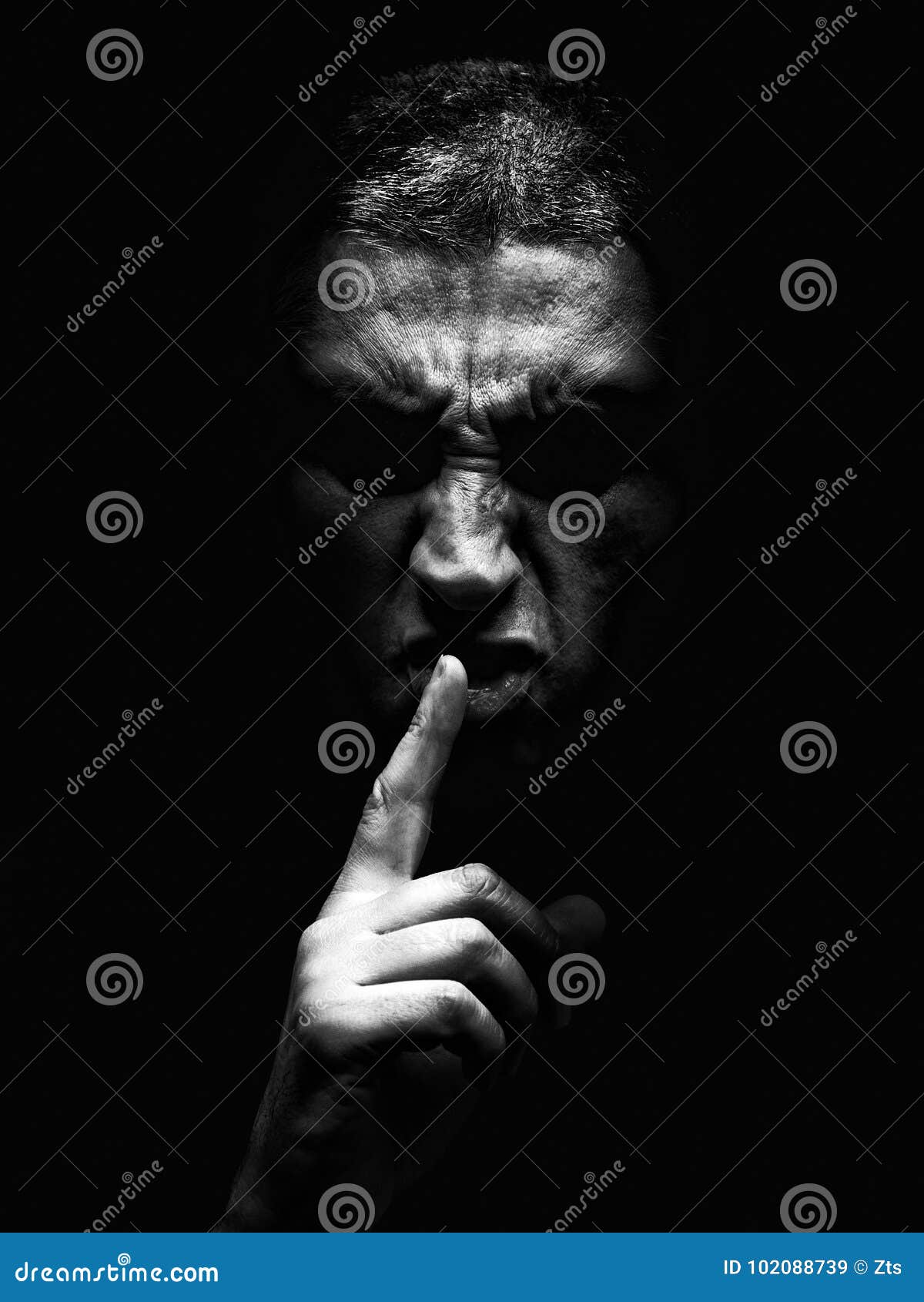 furious mature man with an aggressive look making the silence sign in a violent and threatening way.