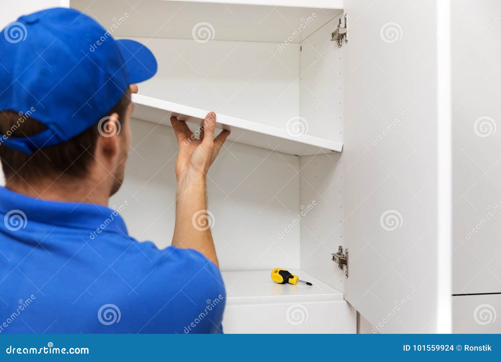 furniture assembly - worker installing cabinet shelf