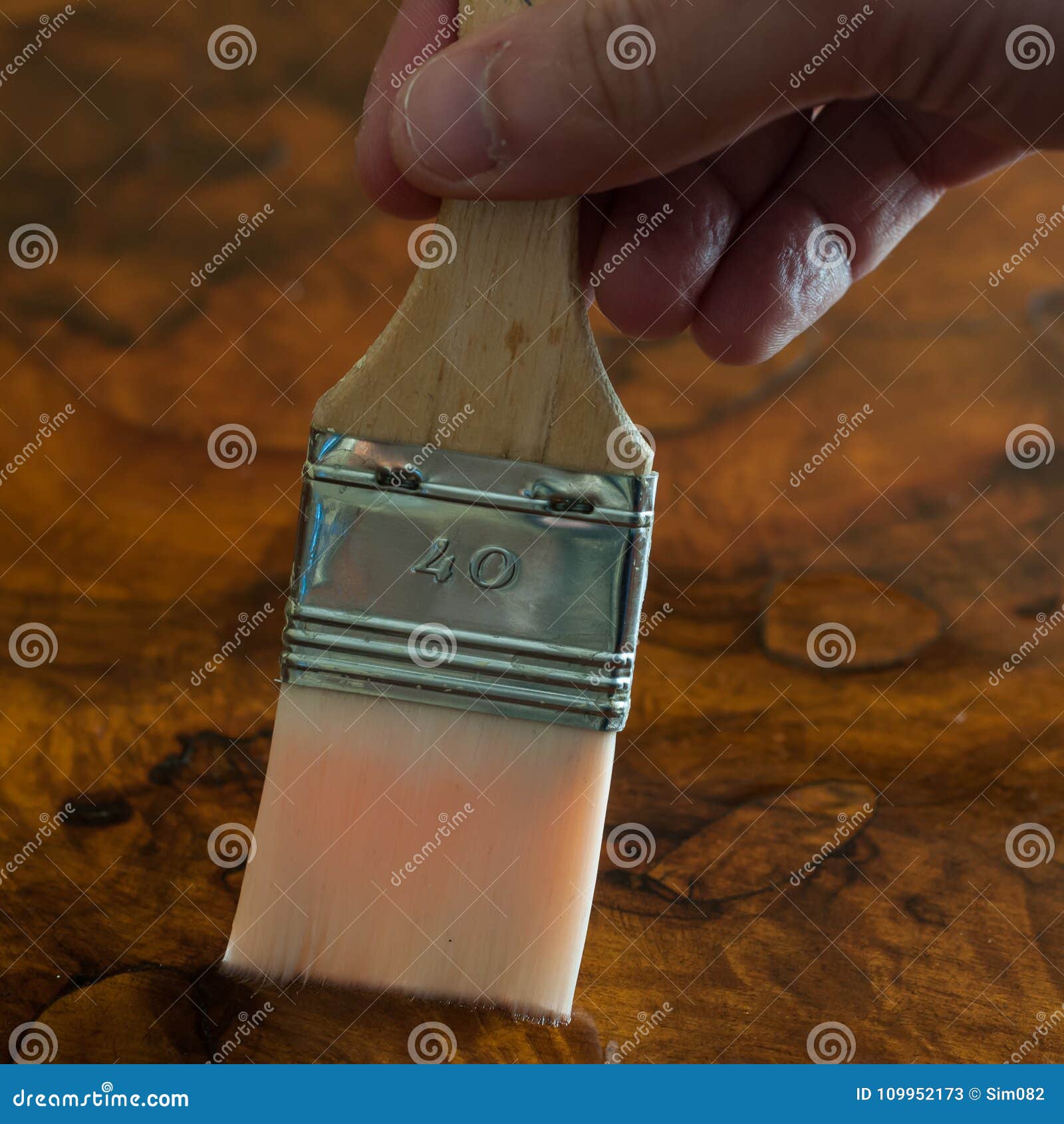 furniture restoration. hand oiling a wood table with a brush.