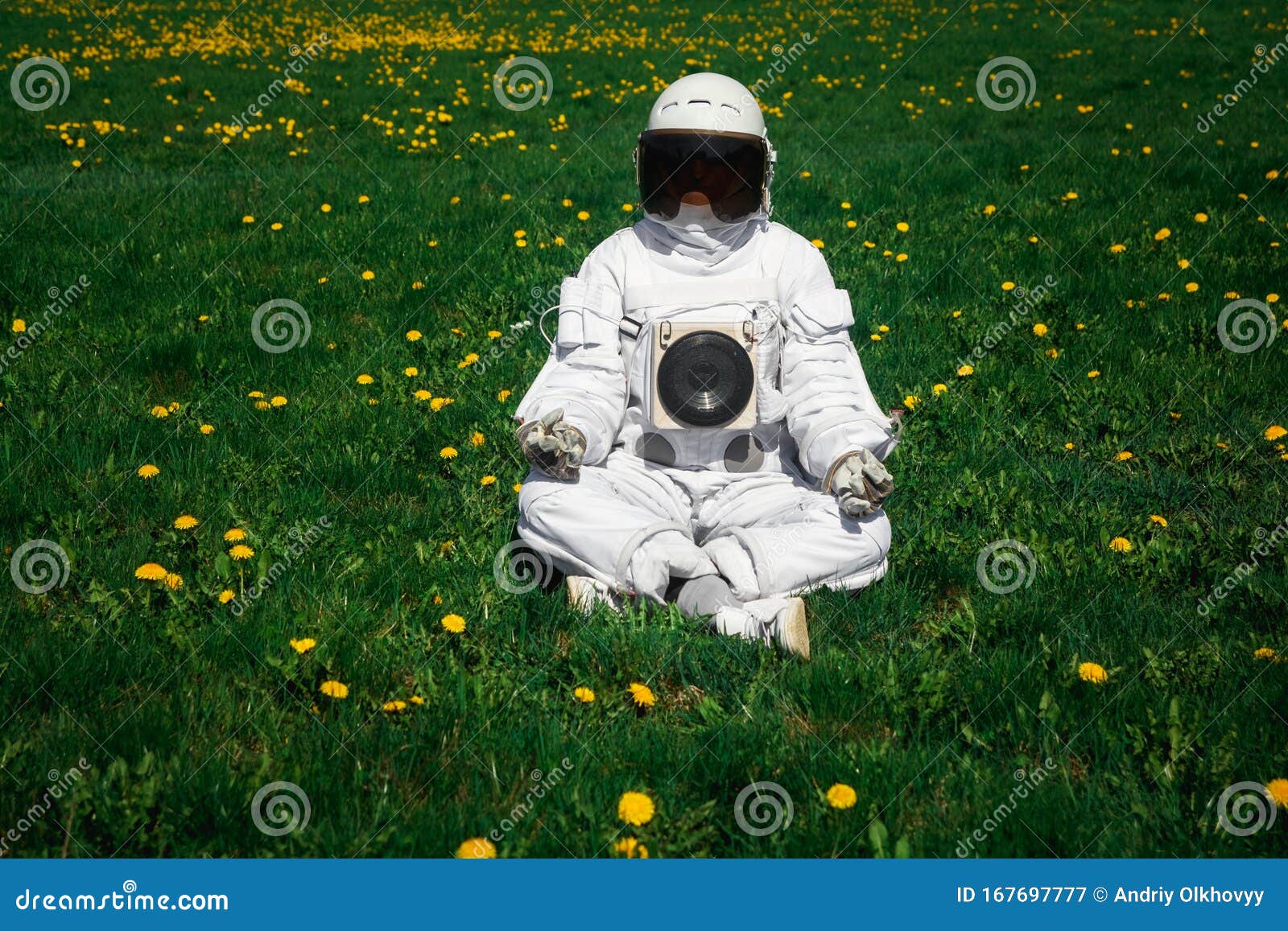 futuristic astronaut in a helmet sits on a green lawn among flowersin a meditative position