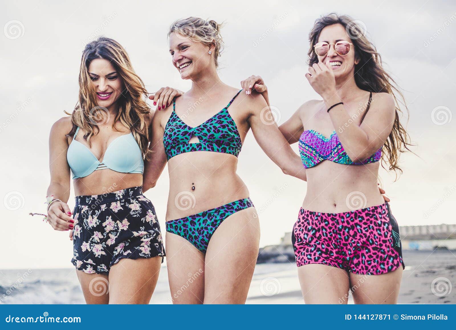 Férias de verão com três jovens mulheres bonitas turistas caminhando com bikini juntas em amizade na praia com céu limpo em segundo plano
