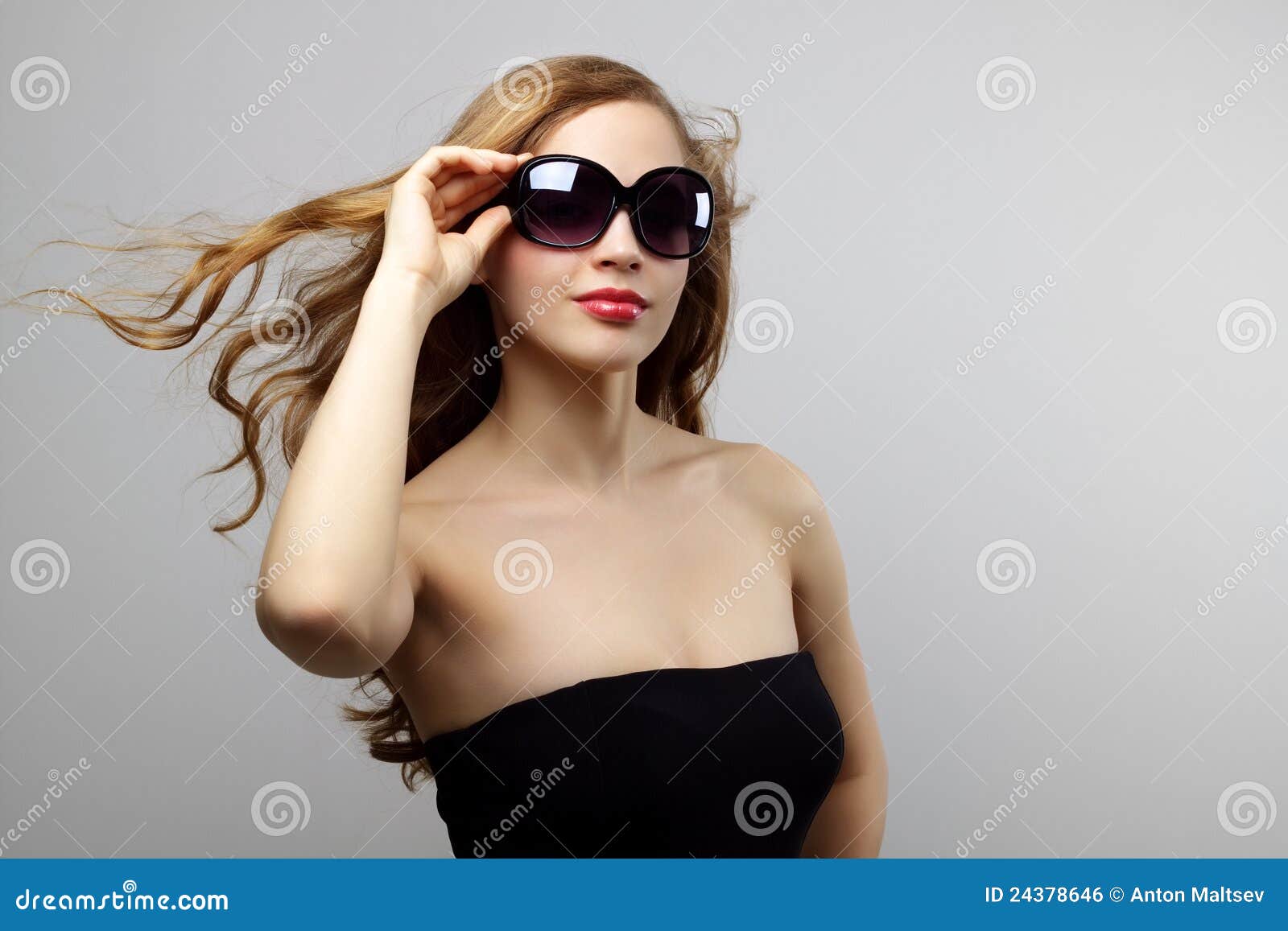 Gafas de sol que desgastan de la señora de moda en fondo gris