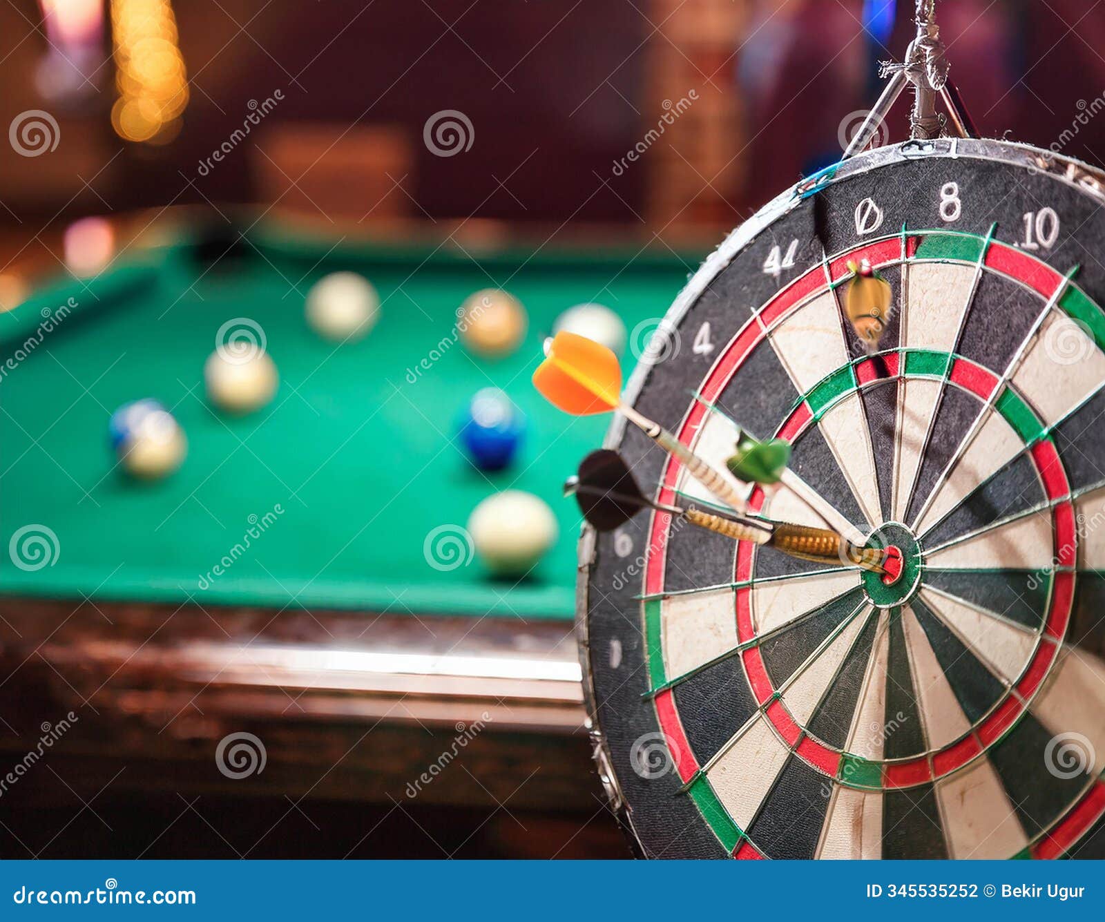 games. darts in a dart board with a pool game in the background(shallow dof)