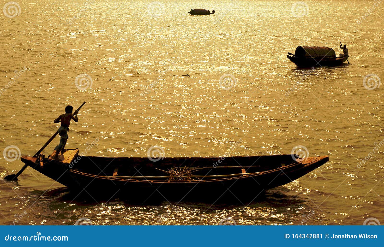 ganges delta, bangladesh: a boat being paddled on the river and silhouetted against the sun