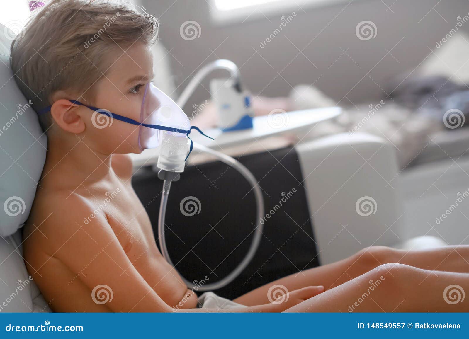 petit garçon malade avec inhalateur pour le traitement de la toux. enfant  malade faisant de l'inhalation sur son lit. saison de la grippe.  intervention médicale à domicile. intérieur et vêtements aux couleurs