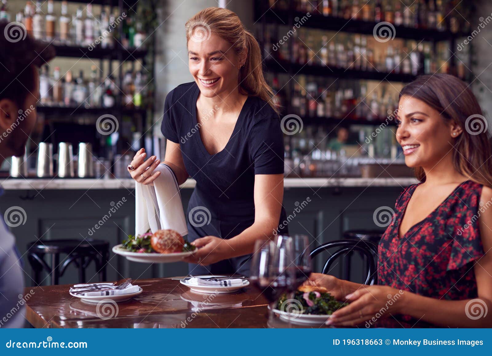 Garçonete De Restaurante Servindo Mesa Com Comida Imagem de Stock