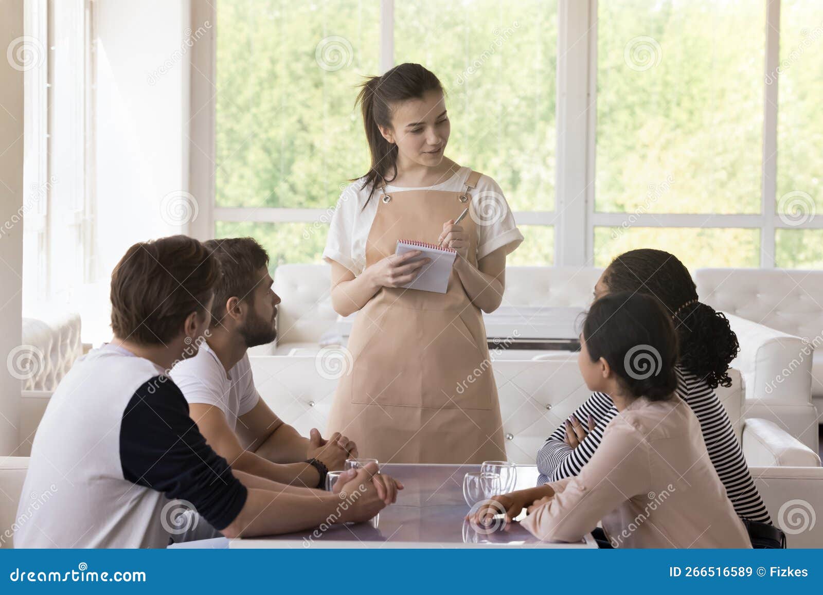 Garçonete bonita servindo grupo de amigas com comida no restaurante