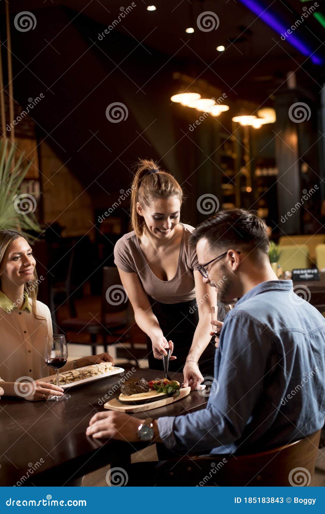 Garçonete bonita servindo grupo de amigas com comida no restaurante