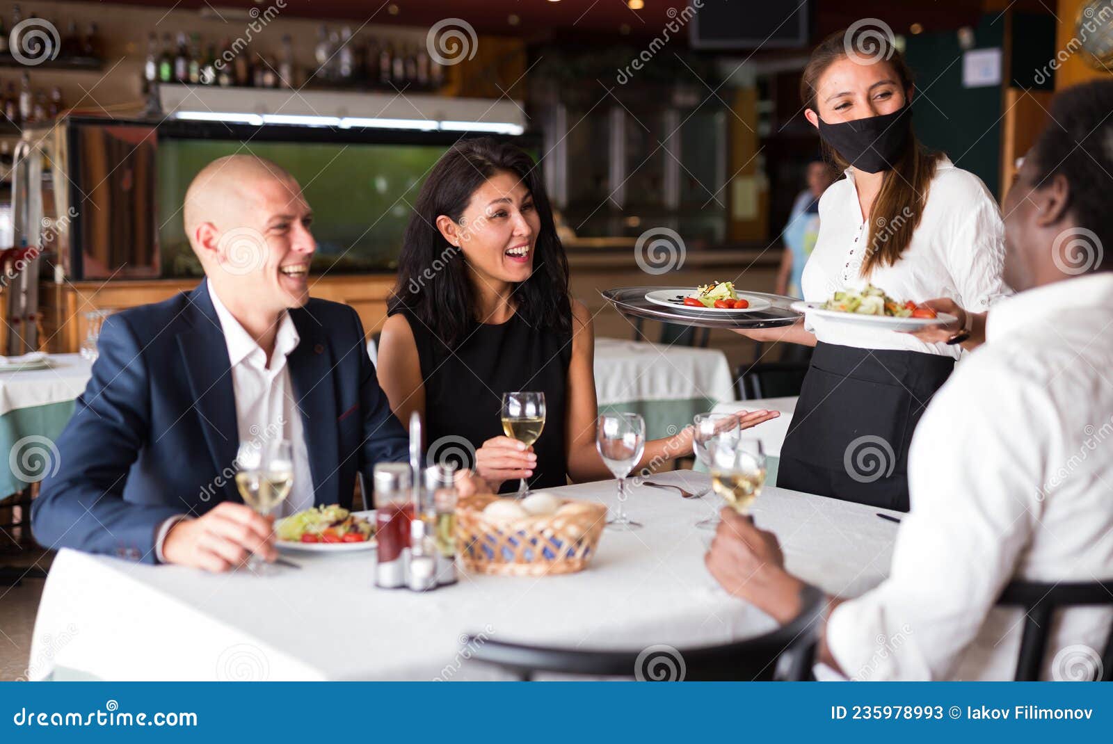 Garçonete bonita servindo grupo de amigas com comida no restaurante