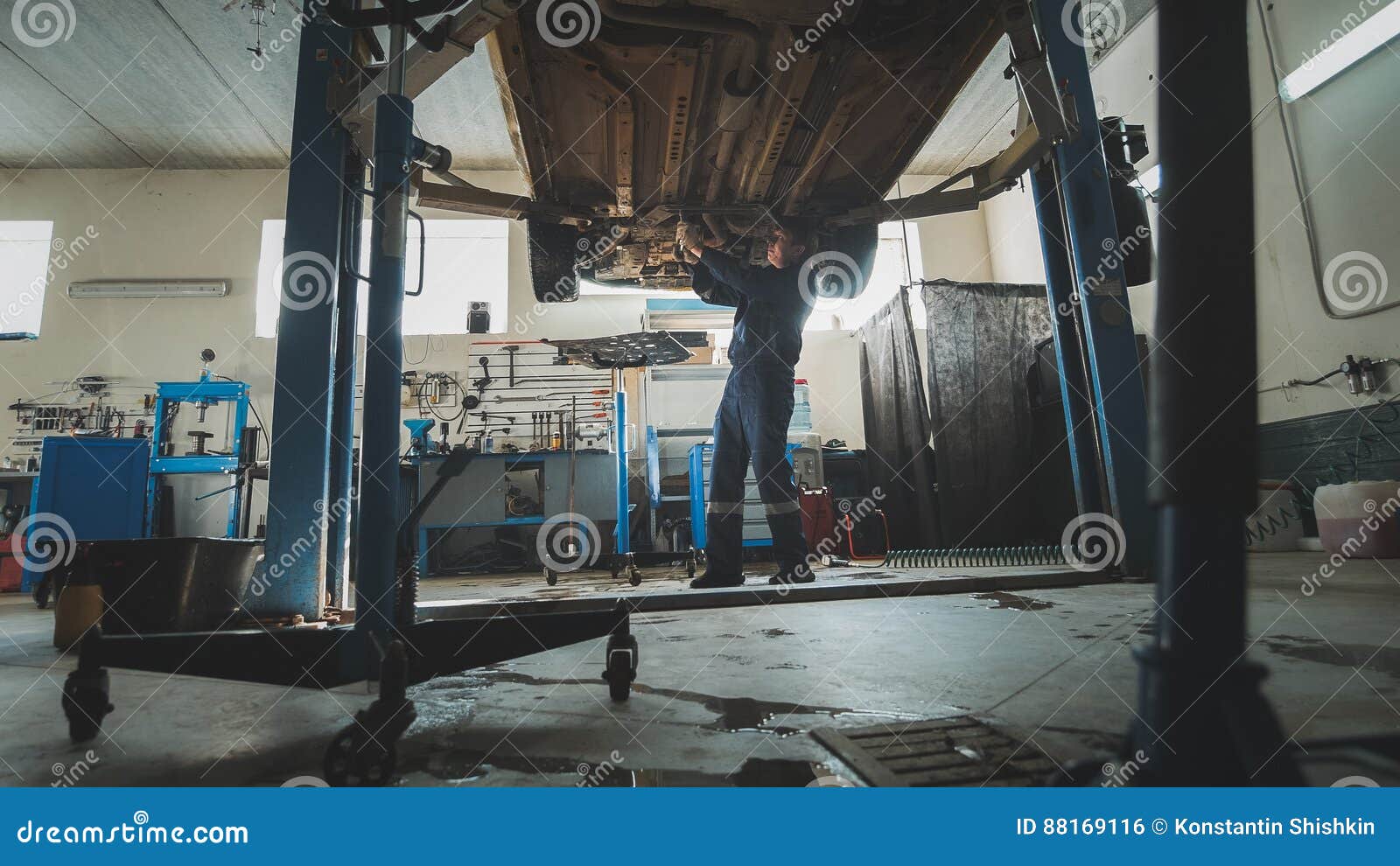 Garage Mechanical Mechanic Checks Bottom of Car Lifted