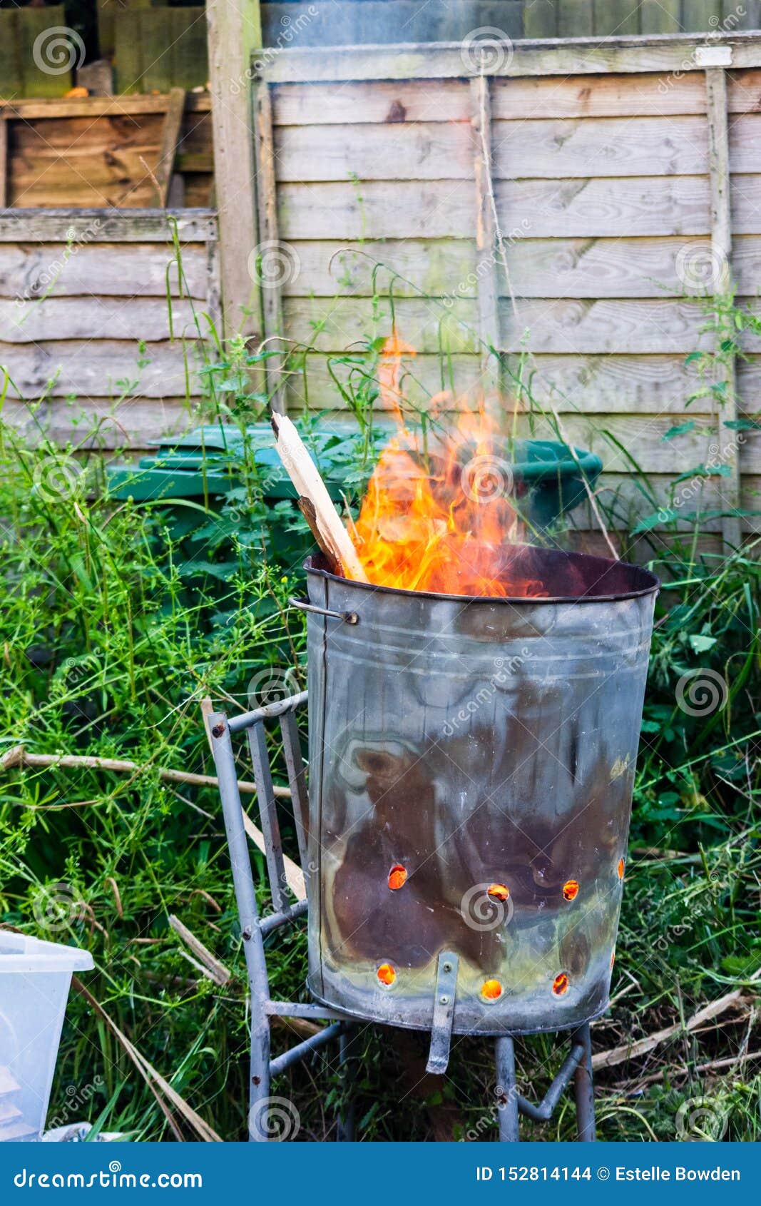 A Garden Incinerator Bin Rested on a Metal Chair Frame Burning