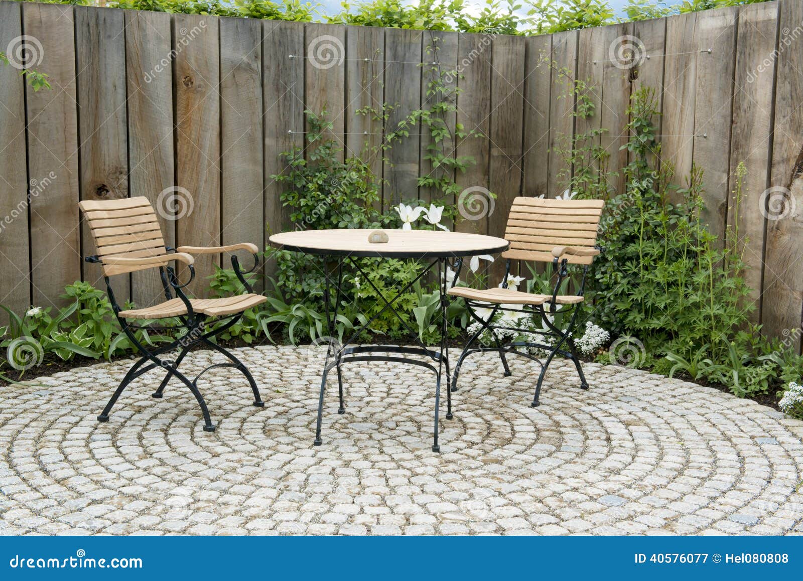 garden patio with round table and two chairs. outdoor furniture made of iron and wood material