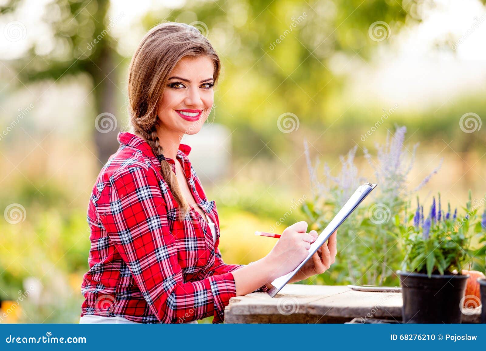 gardener holding clipboard, at the table, green sunny nature