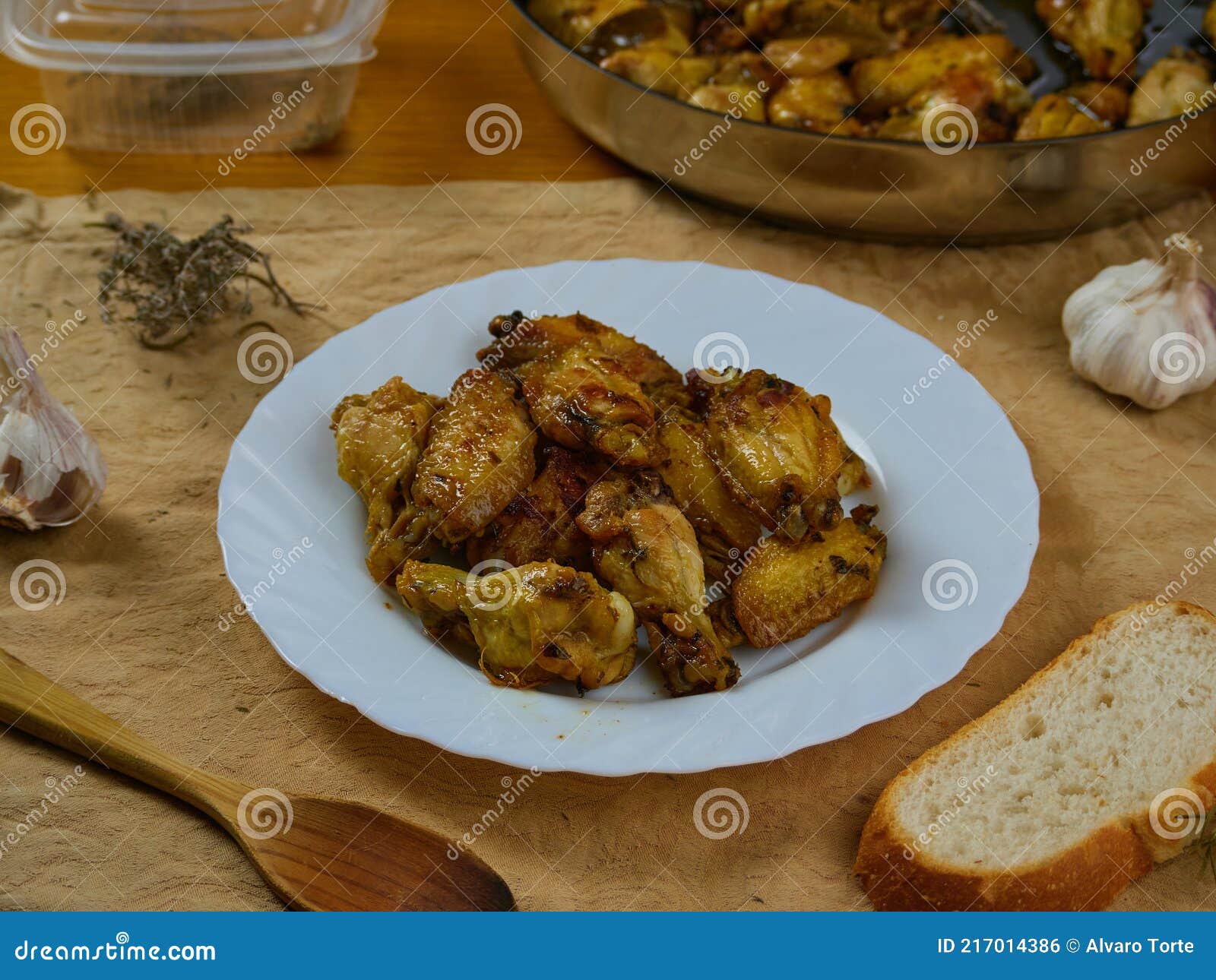 garlic chicken wings pollo al ajillo. delicious spanish tapa dish served with crusty bread, a paellera pan and its ingredients
