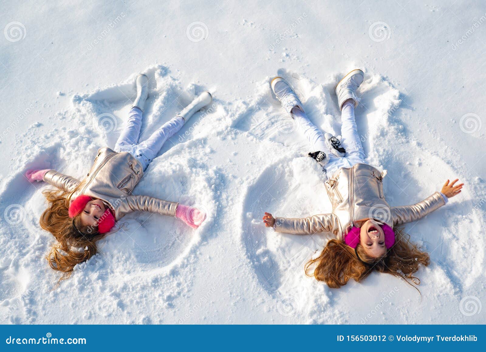 Garota feliz em shows de anjo de neve. Duas garotinhas fazendo anjo de neve enquanto deitado na neve