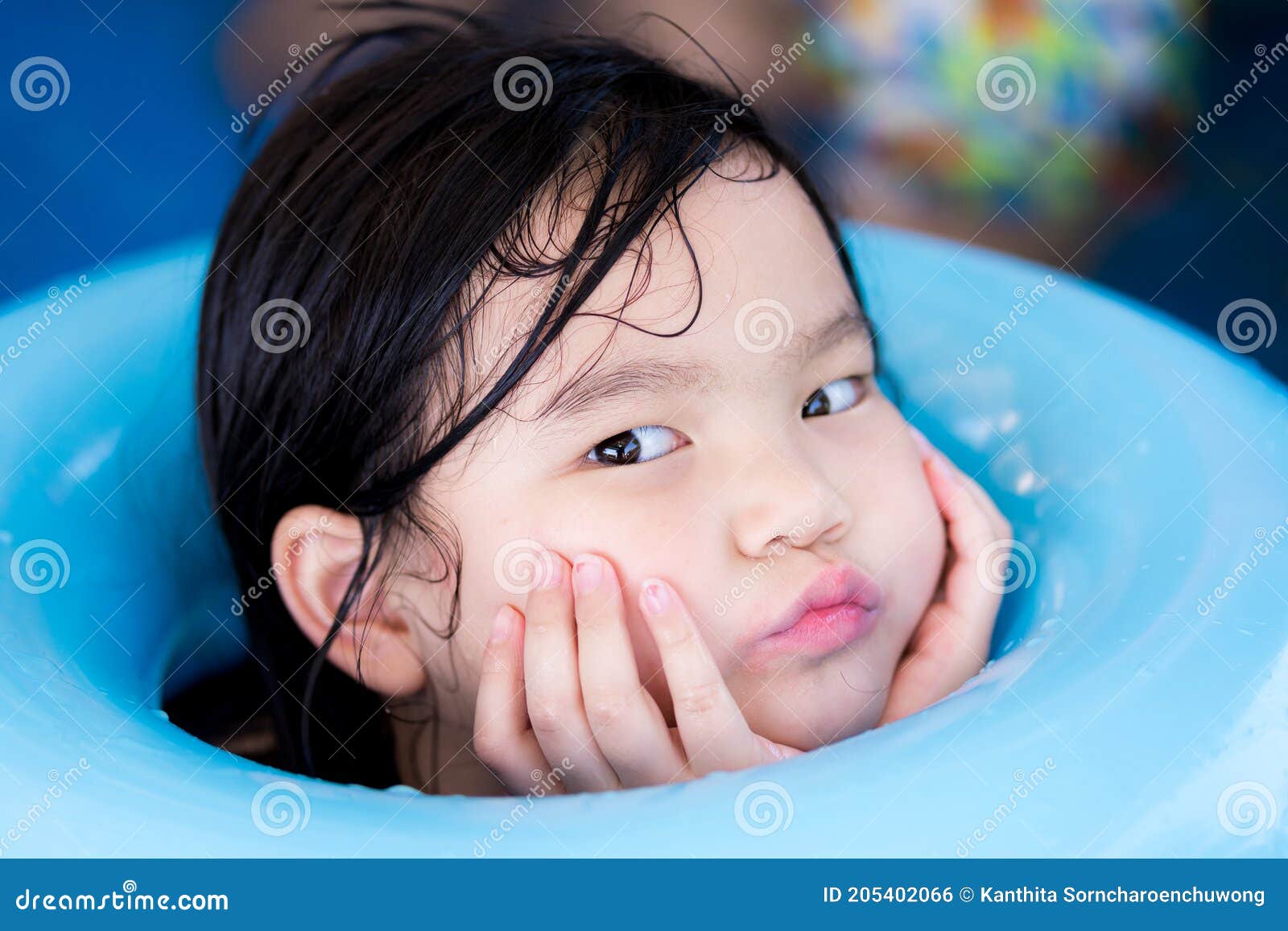 Menina bonita de 5 anos com cabelos escuros em um maiô azul de