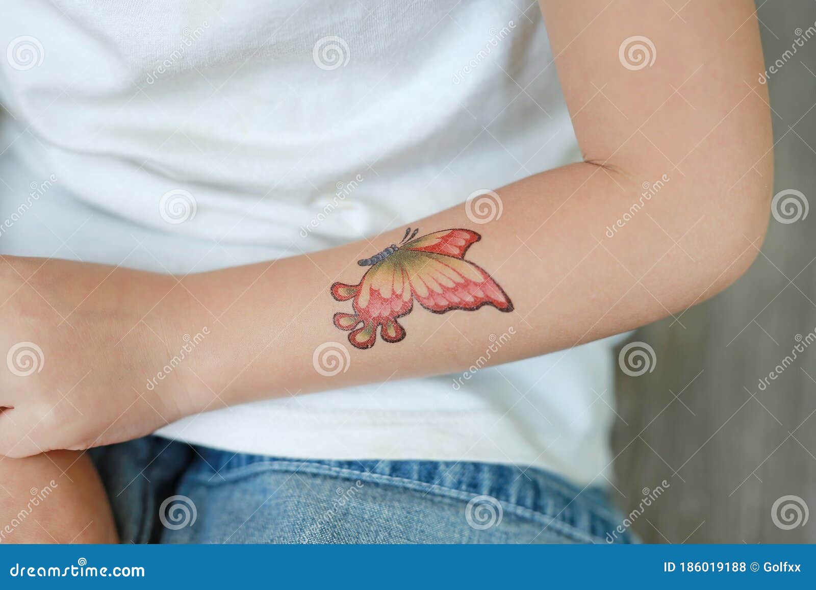 Garotinha De Camisola Com Adesivo De Tatuagem De Borboleta Na Mão