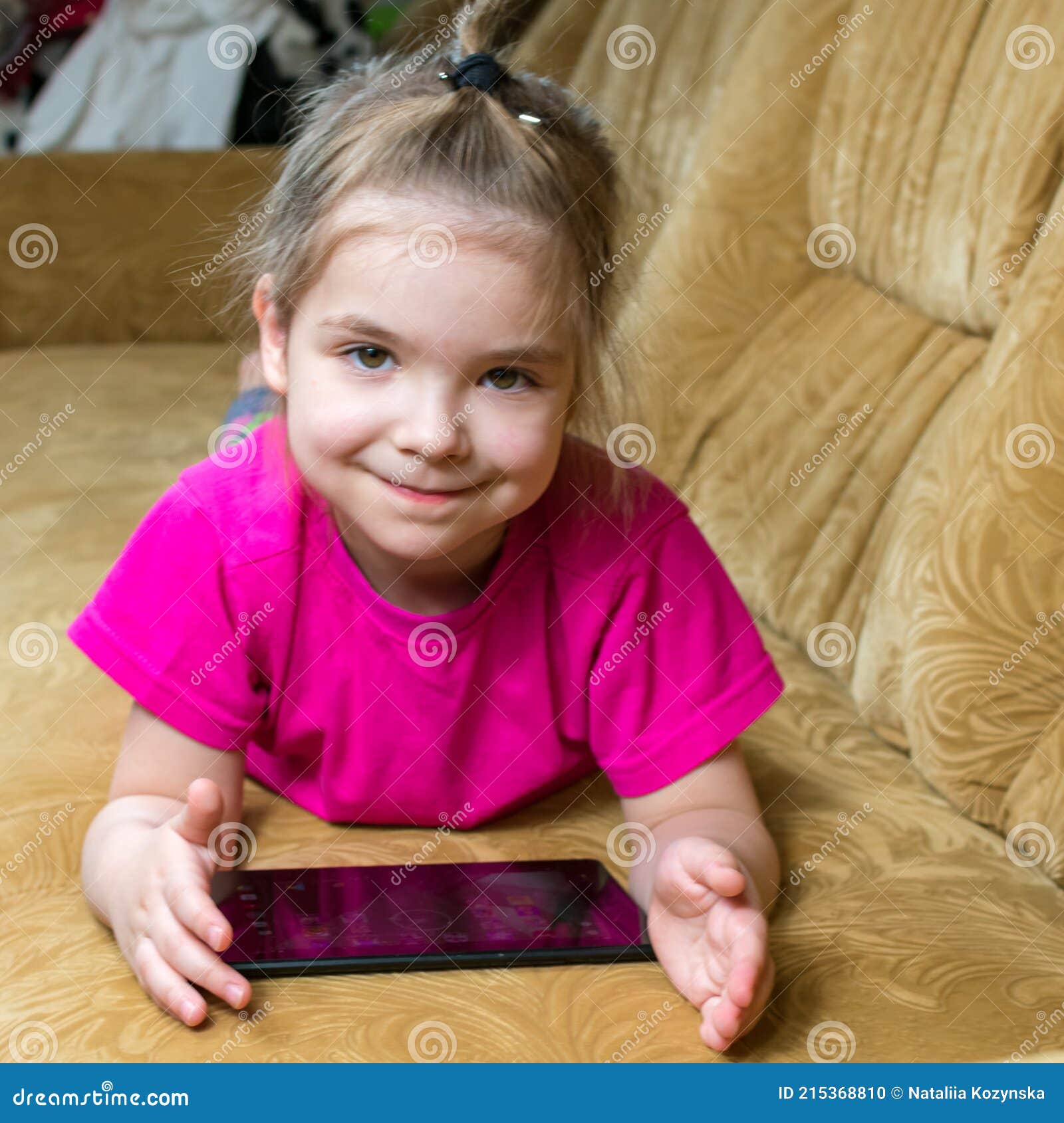 Sorridente menina deitada no sofá confortável, gostando de jogar jogo  online no computador tablet digital. viciado em tecnologia, criança feliz  usando aplicativos engraçados, informações de navegação na web.