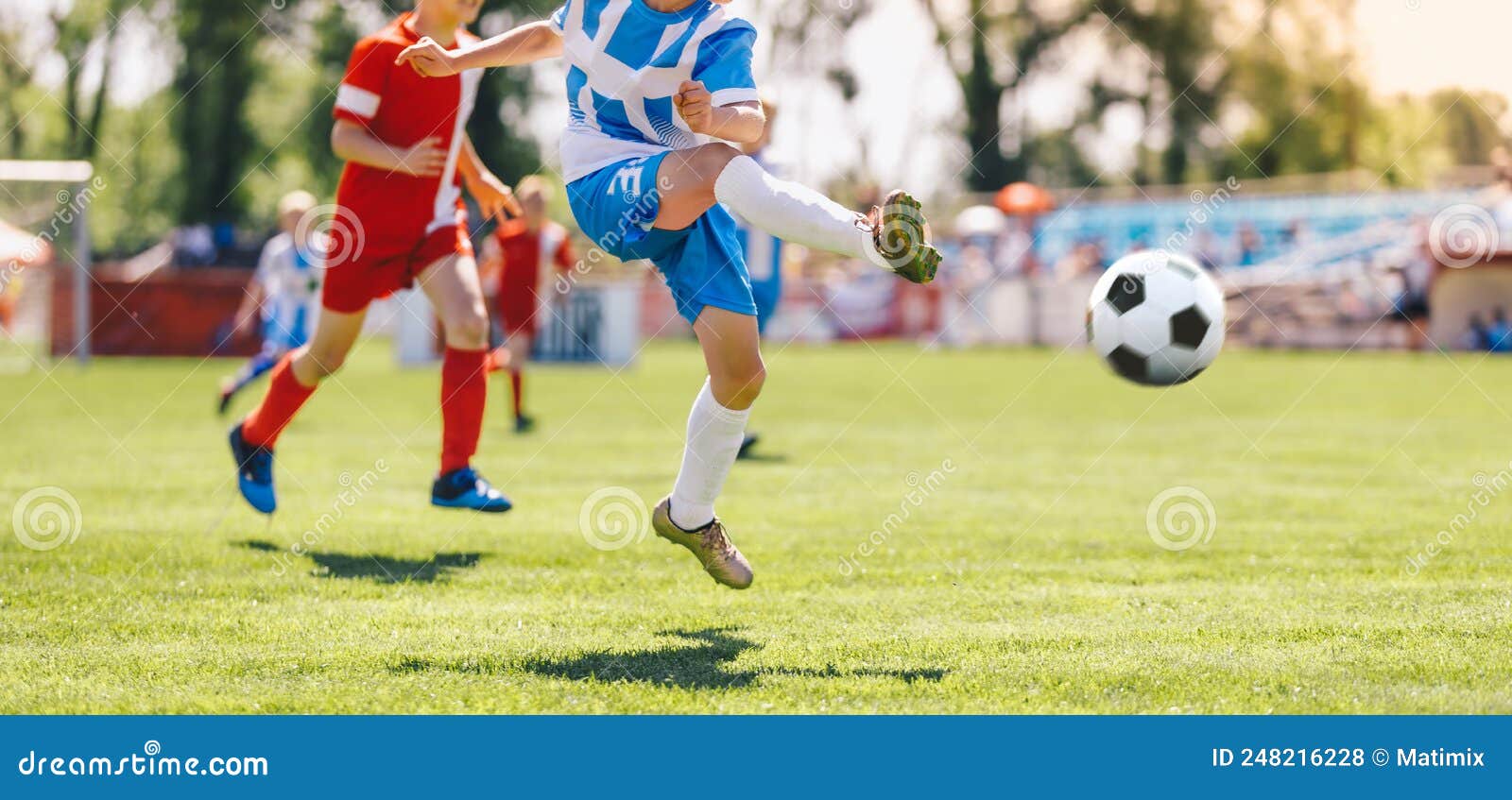 Dois Jogadores De Futebol Chutando Bola De Futebol Em Um Jogo. Meninos Da  Escola Jogam Competição Esportiva. Duas Crianças Multirraciais Jogando  Partida De Futebol. Crianças Em Uniformes De Futebol Verde E Azul