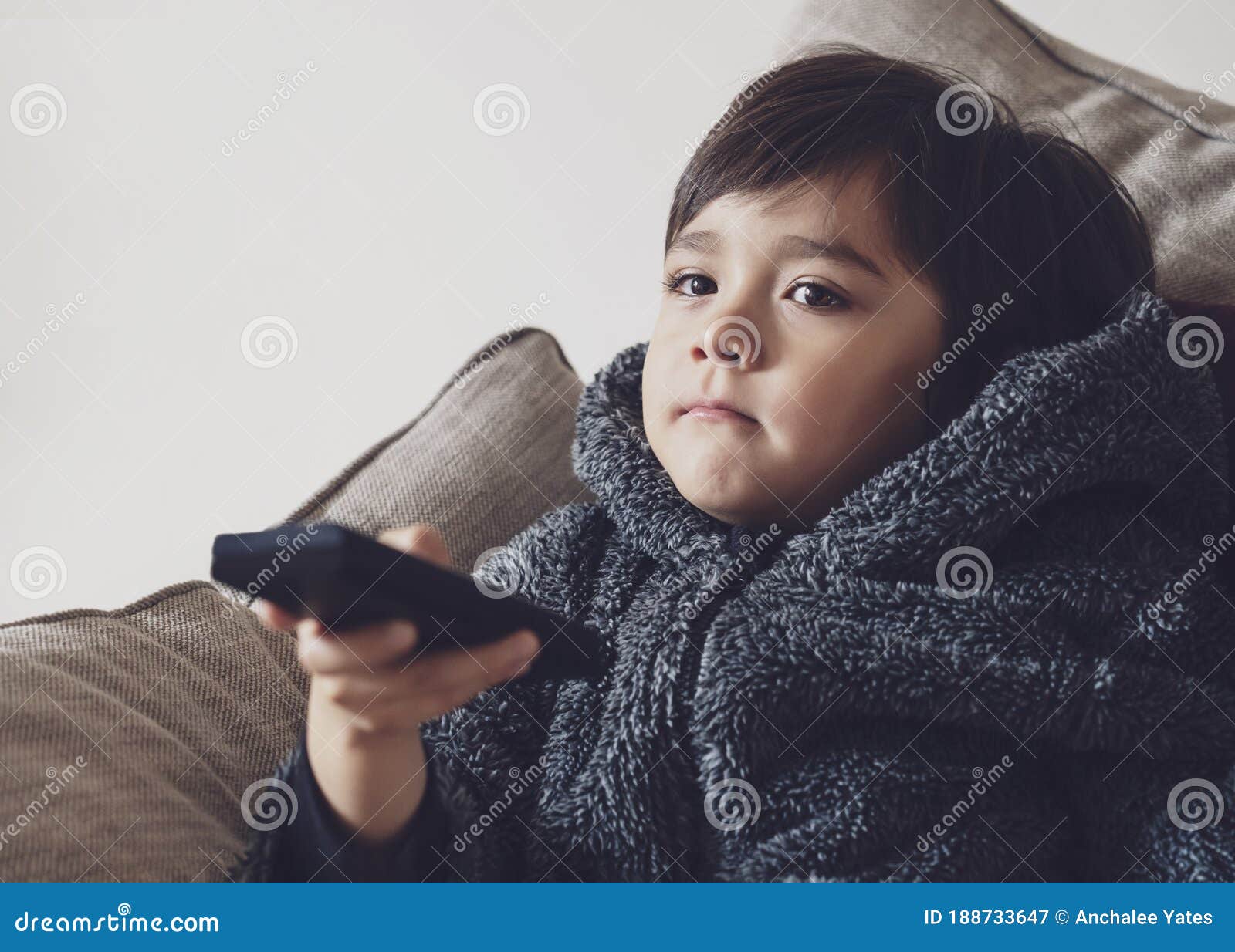 Menino feliz segurando o controle remoto e olhando para cima com