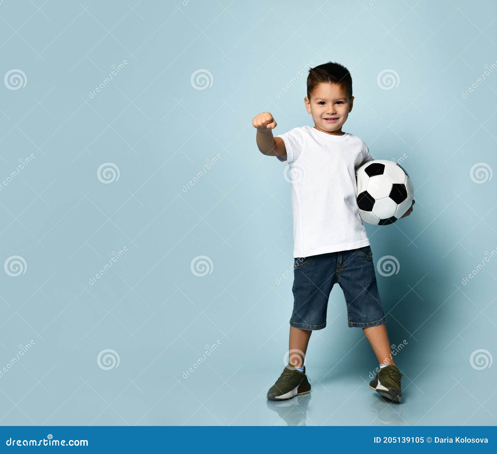 Um garoto segurando a velha bola de futebol antes de começar um jogo de  futebol