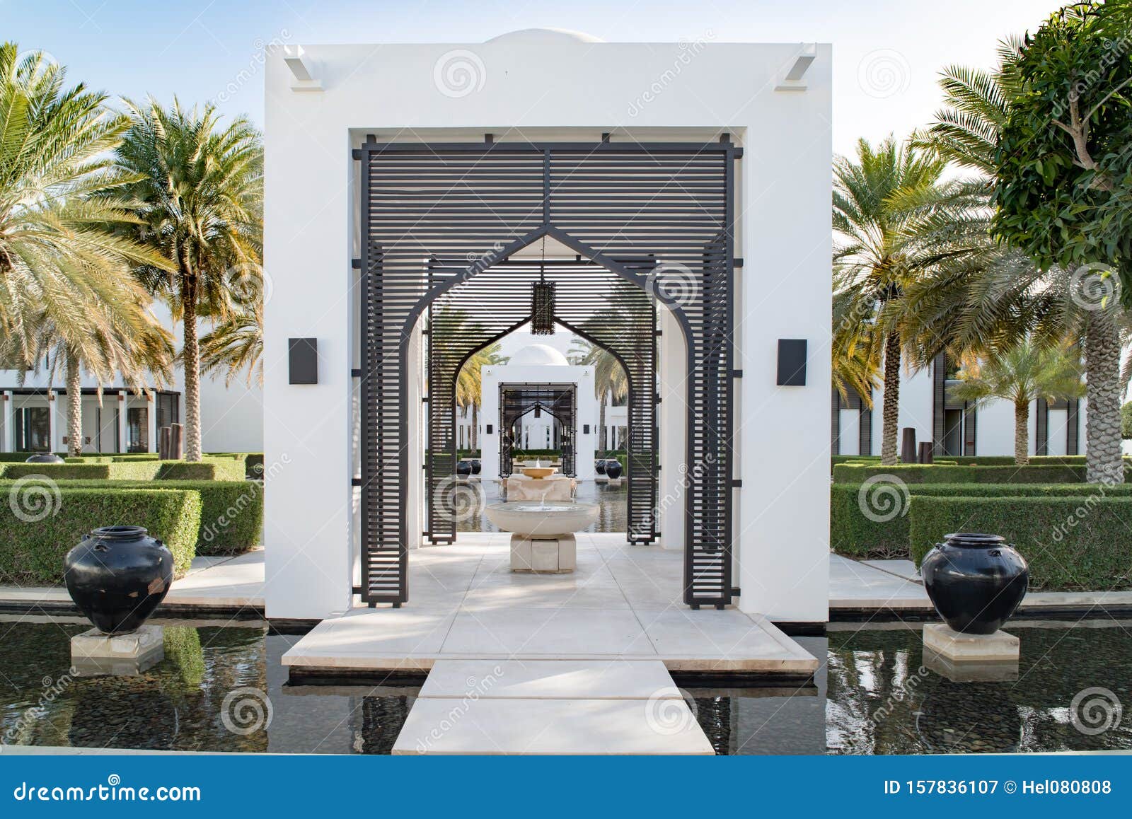 Garten mit Wasserbecken und Pfad mit orientalischen Toren im luxuriösen Hotelstil asiatisch. Schöner formaler Garten mit Wasserbecken und Amphoren, Brücke mit Toren in Luxusresort