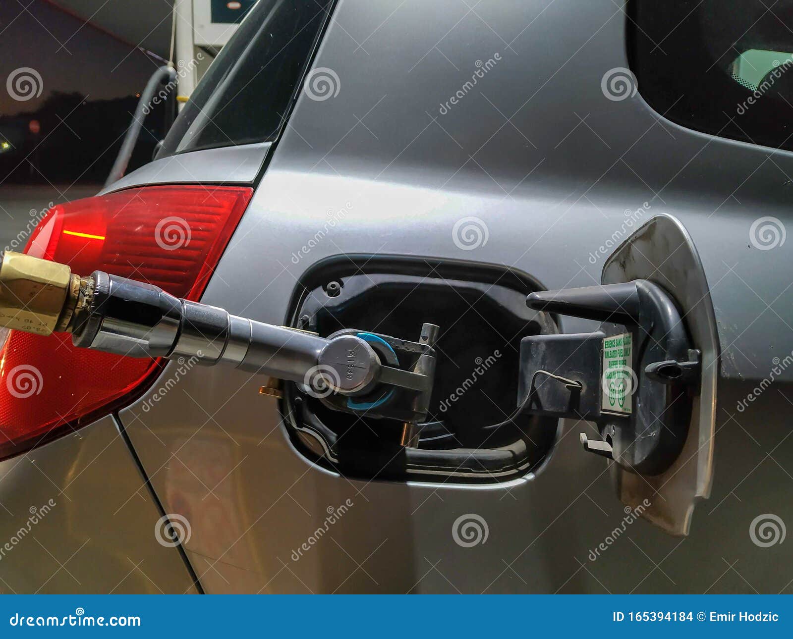 Gas Hose Pumping Gas into Grey Car during Nighttime Travel