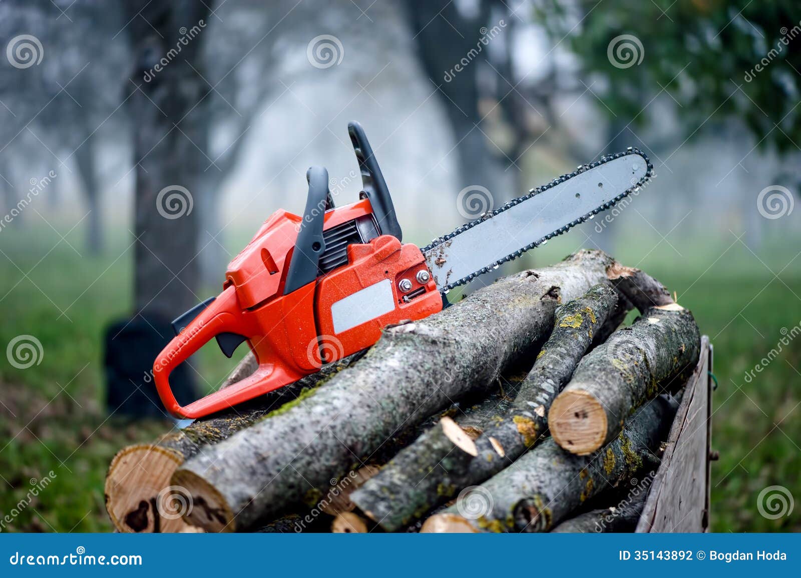 gasoline powered professional chainsaw on pile of cut wood