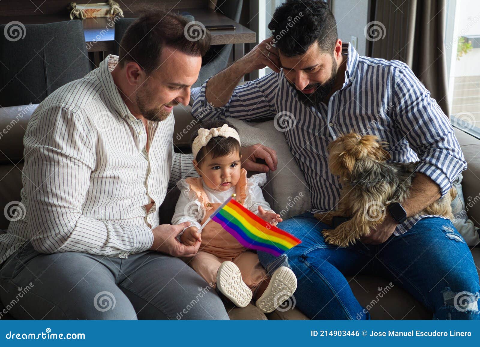Gay Couple with Their Young Daughter and Dog Sitting on the Sofa